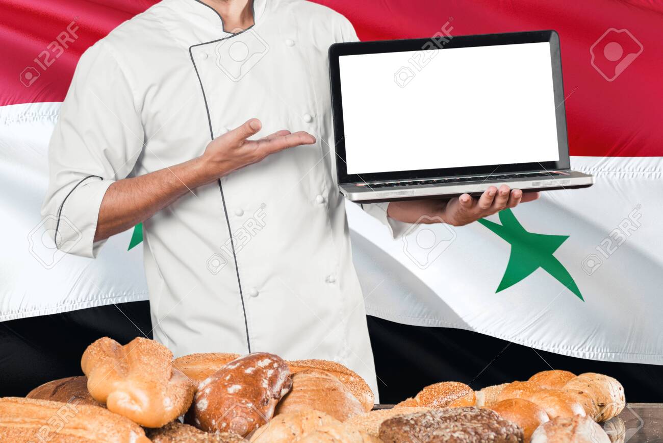 Syrian Baker Holding Laptop On Syria Flag And Breads Background