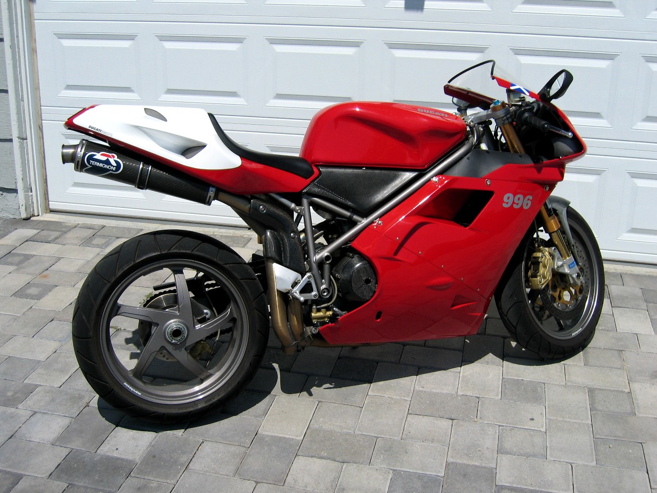 Red and white Ducati 996 sportbike parked in front of a garage