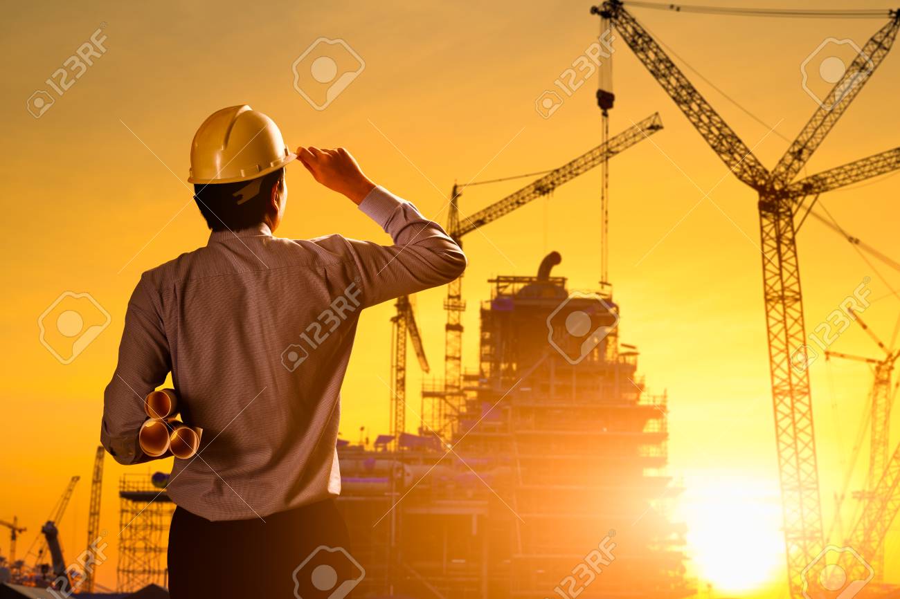 Silhouette Engineer Wear A Helmet At Construction Site With Crane