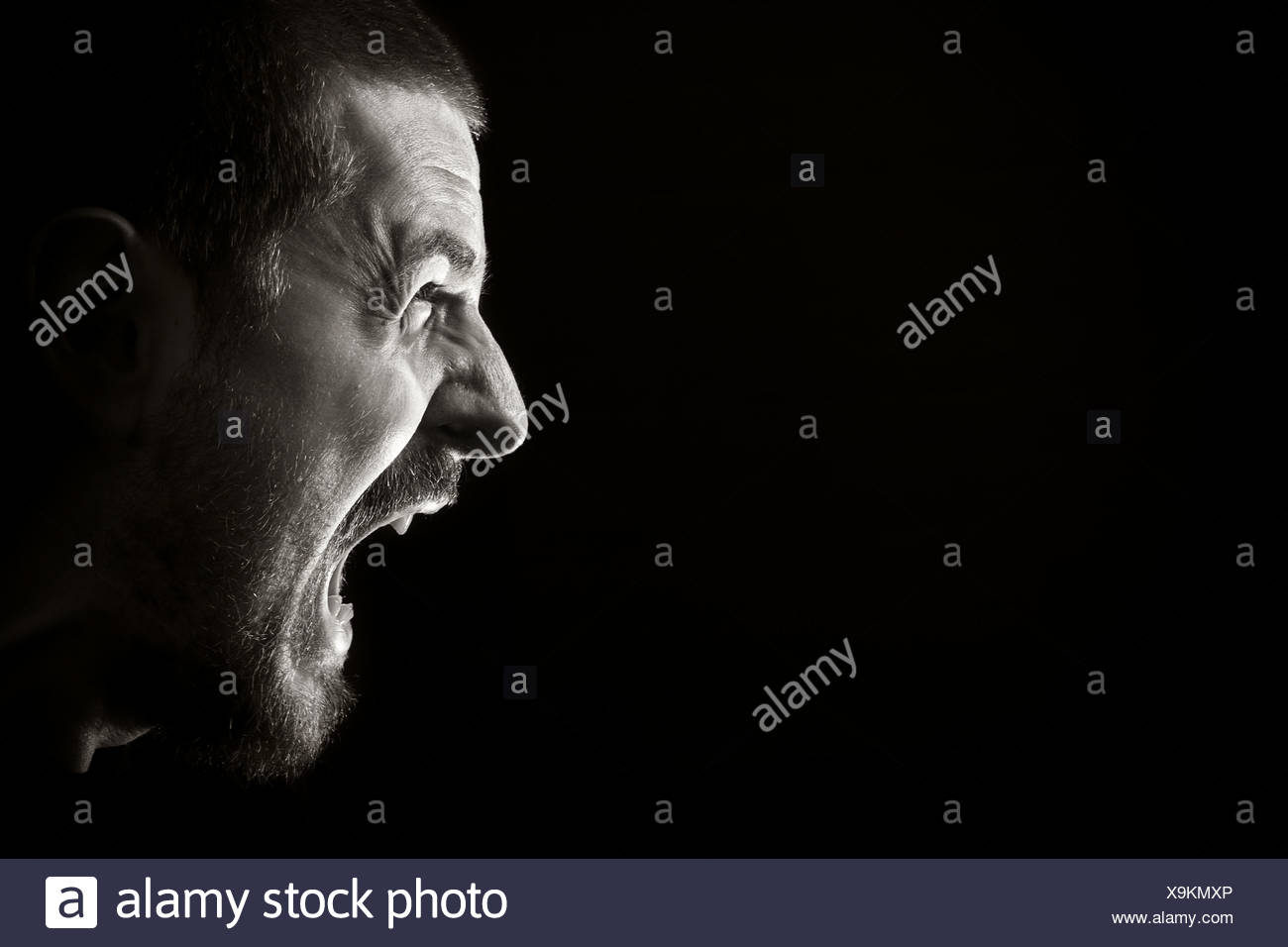 Portrait of screaming angry man on black background Stock Photo