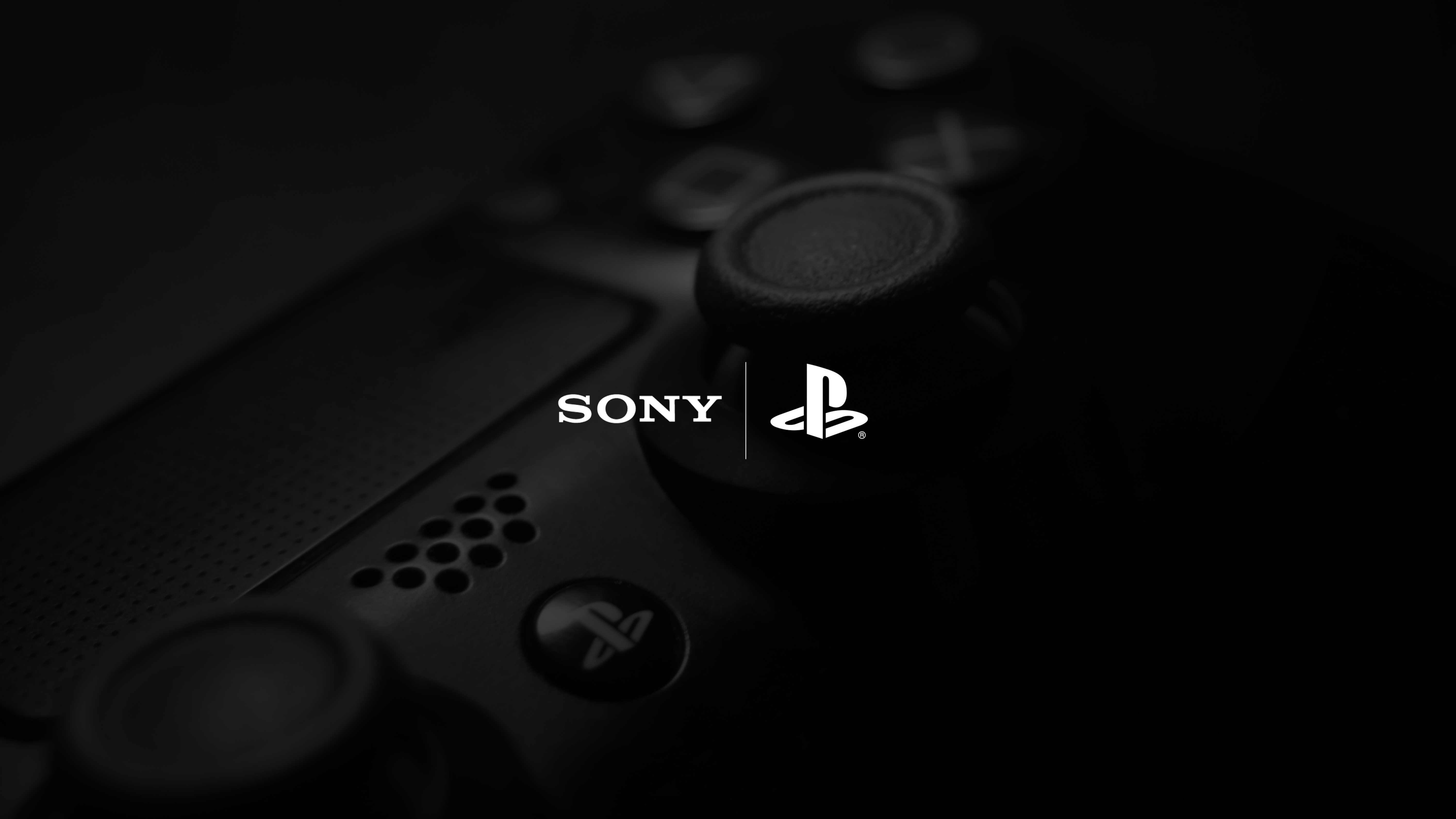 Close-up of a PlayStation controller, highlighting the Sony and PlayStation logos. The focus is on the textured thumbstick and subtle details of the console's design