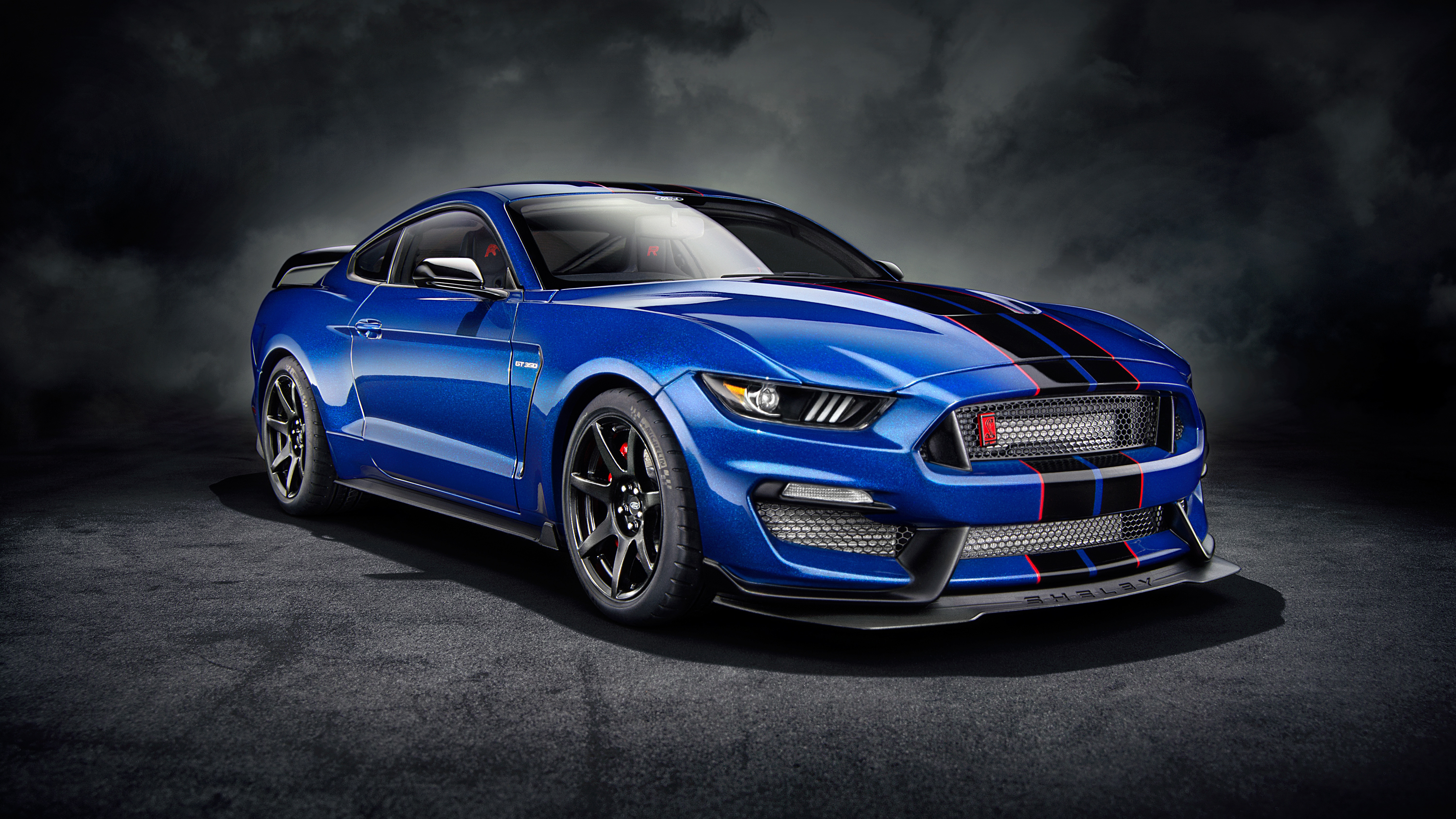 Blue Ford Mustang Shelby GT350R parked on a dark surface with smoke in the background