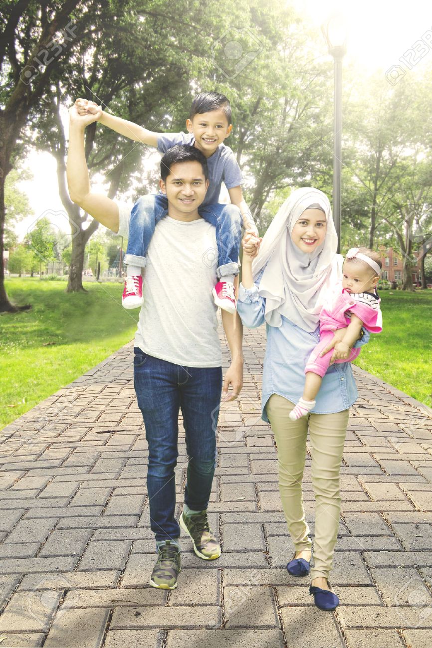 Happy Muslim Family Walking In The Park Way While Holding Hands
