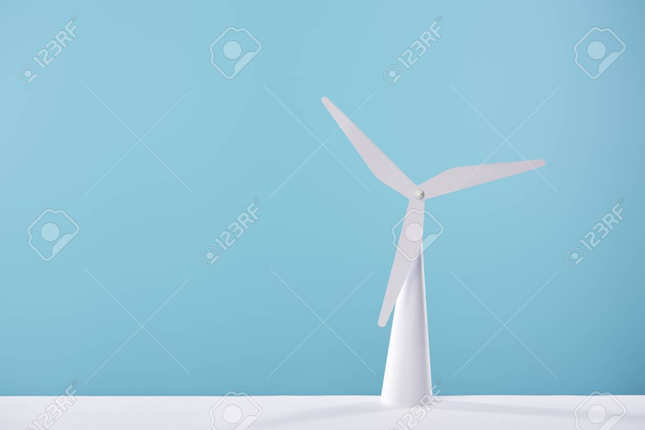 White Windmill Model On Blue Background And Table Stock Photo