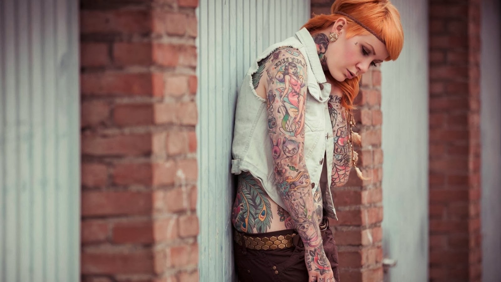 Woman with colorful tattoos leaning against a wall