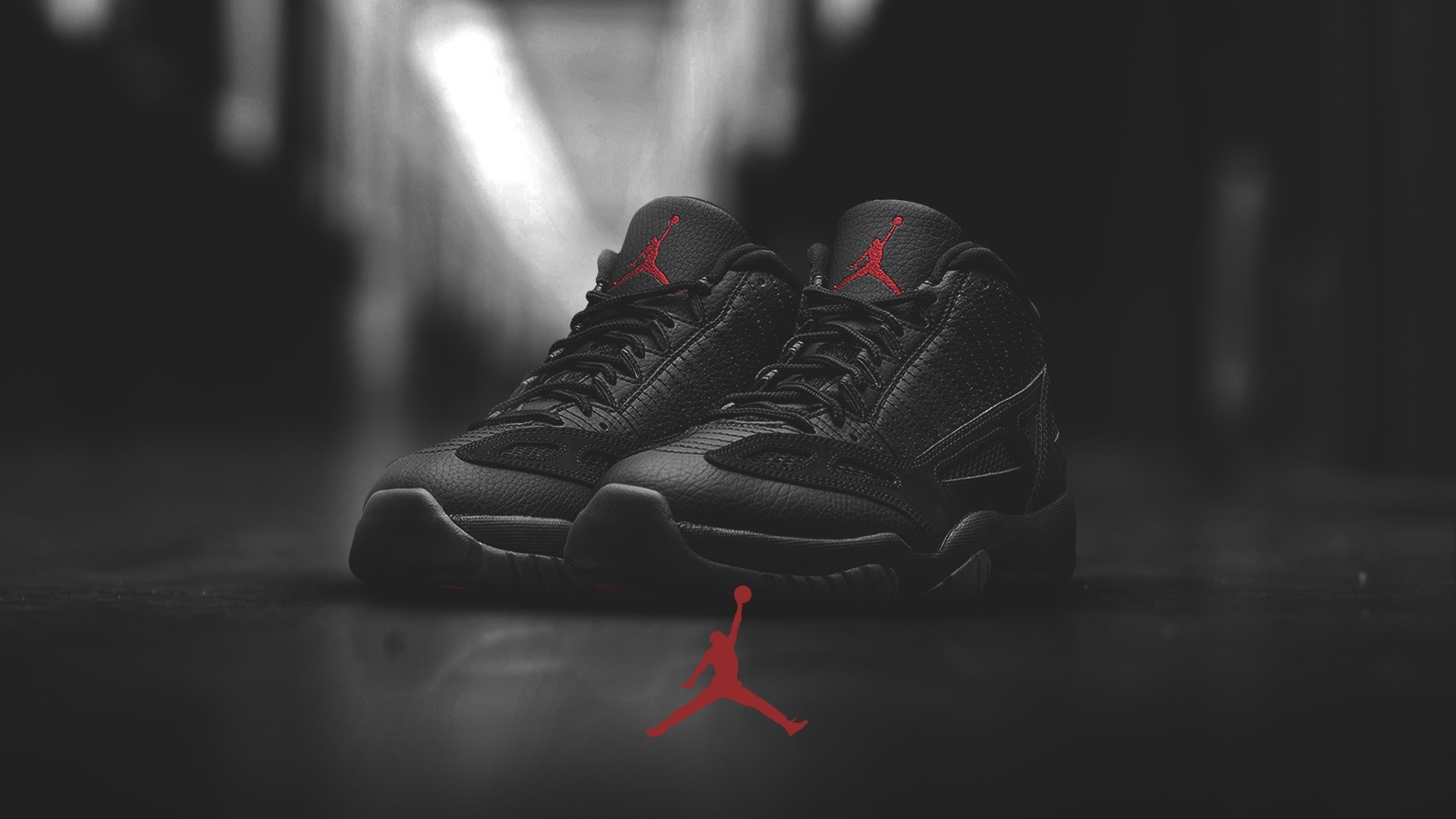 Close-up of a pair of black Air Jordan sneakers on a dark surface, with the iconic Jumpman logo subtly placed below