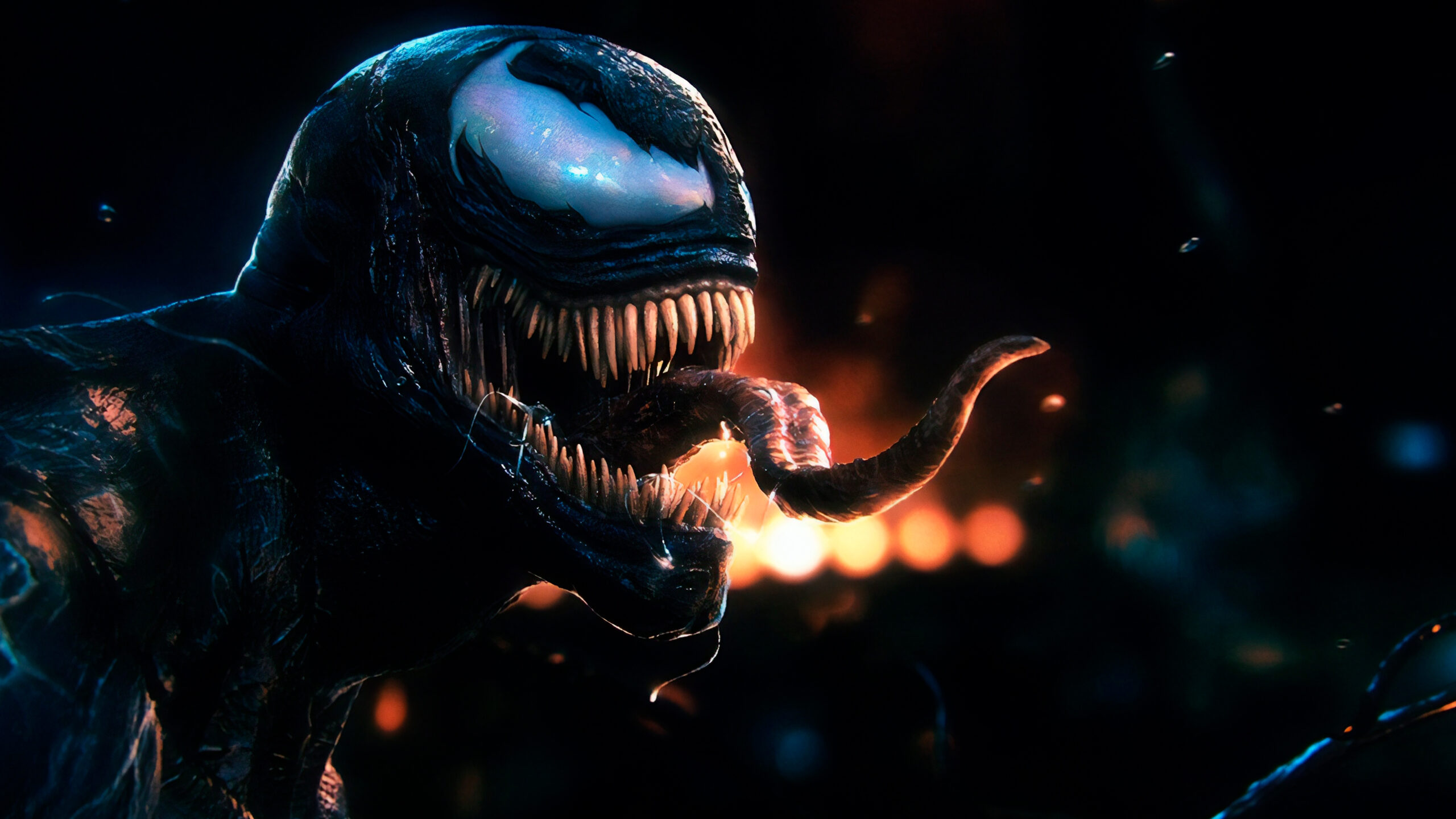 Close-up of Venom's menacing face, featuring sharp teeth, a long tongue, and a backdrop of fiery hues