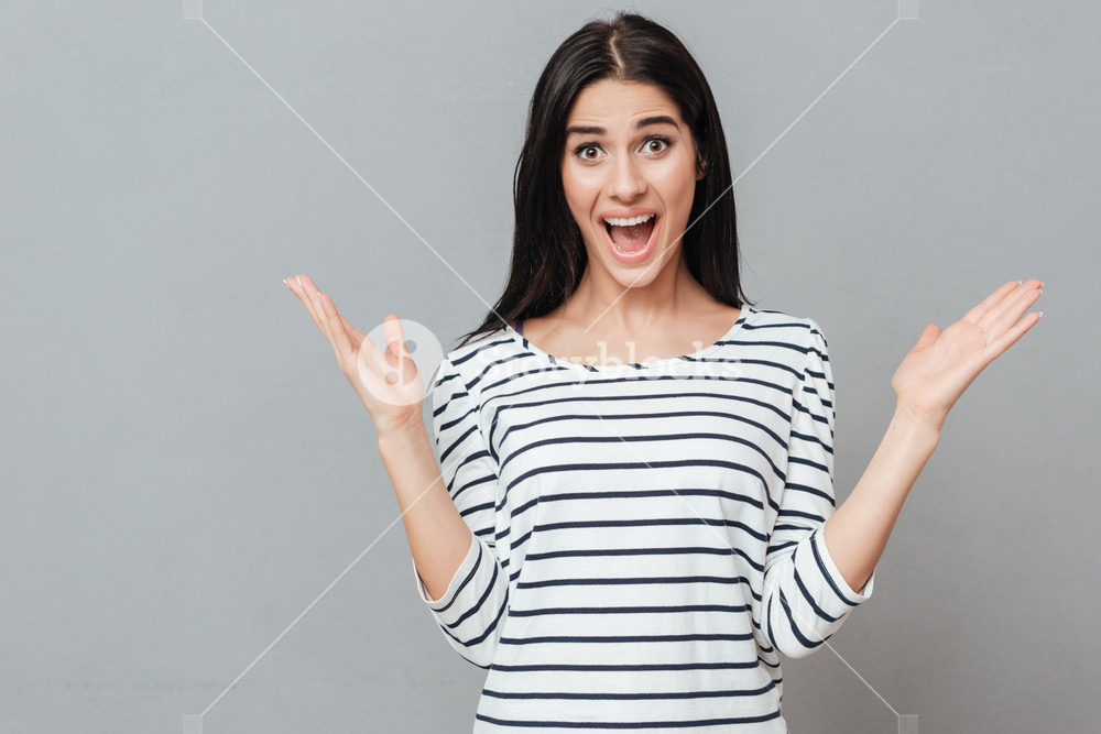 Shocked Young Woman Standing Over Grey Background Look At Camera
