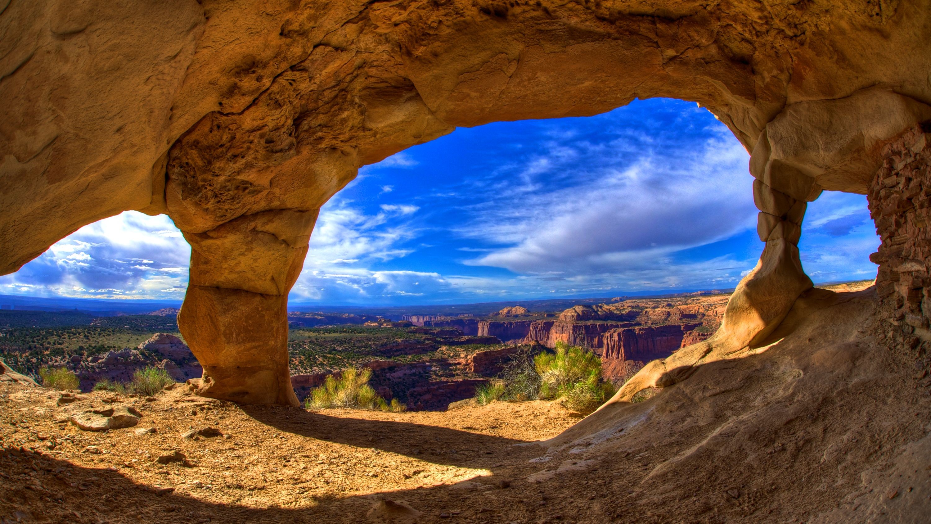 A breathtaking view of a canyon landscape through a natural rock archway, resembling a cave opening