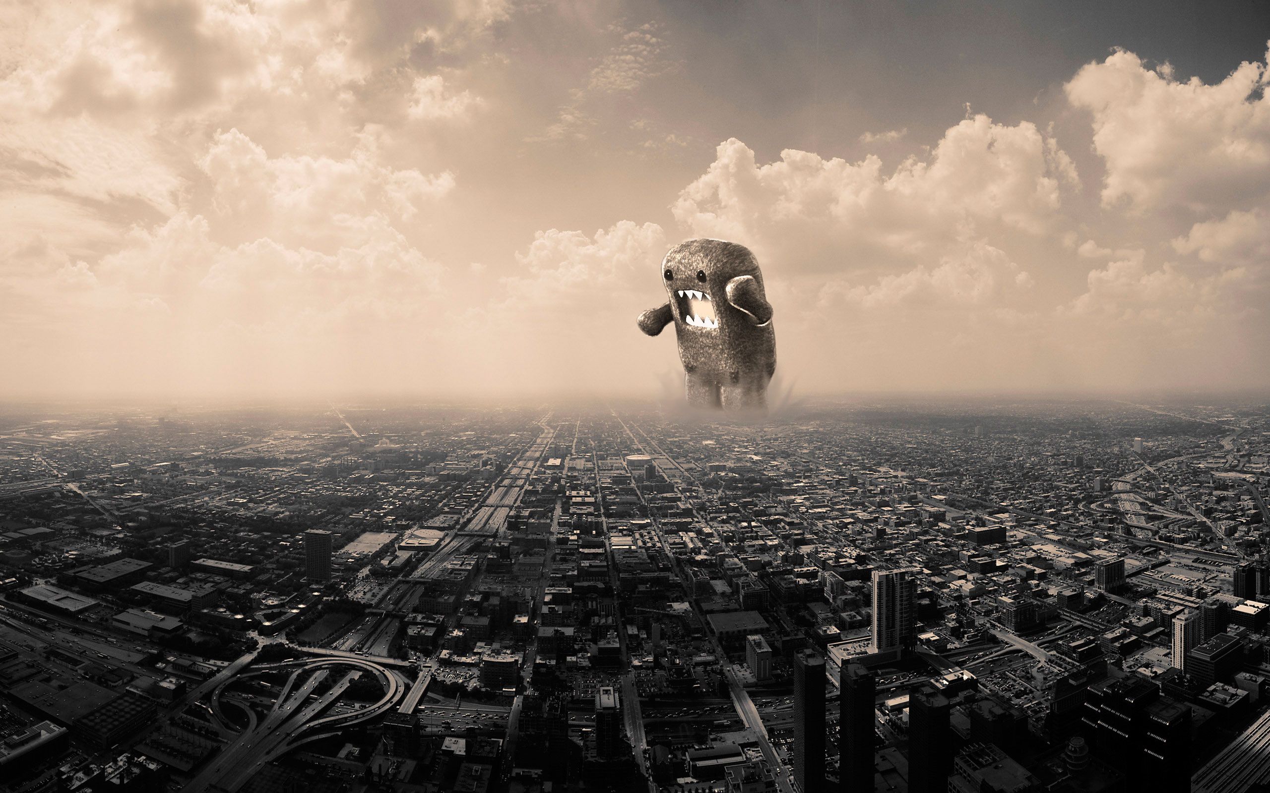 A giant Domo-kun figurine towers over a sprawling cityscape, evoking a sense of playful destruction and urban fantasy in this cool PC wallpaper