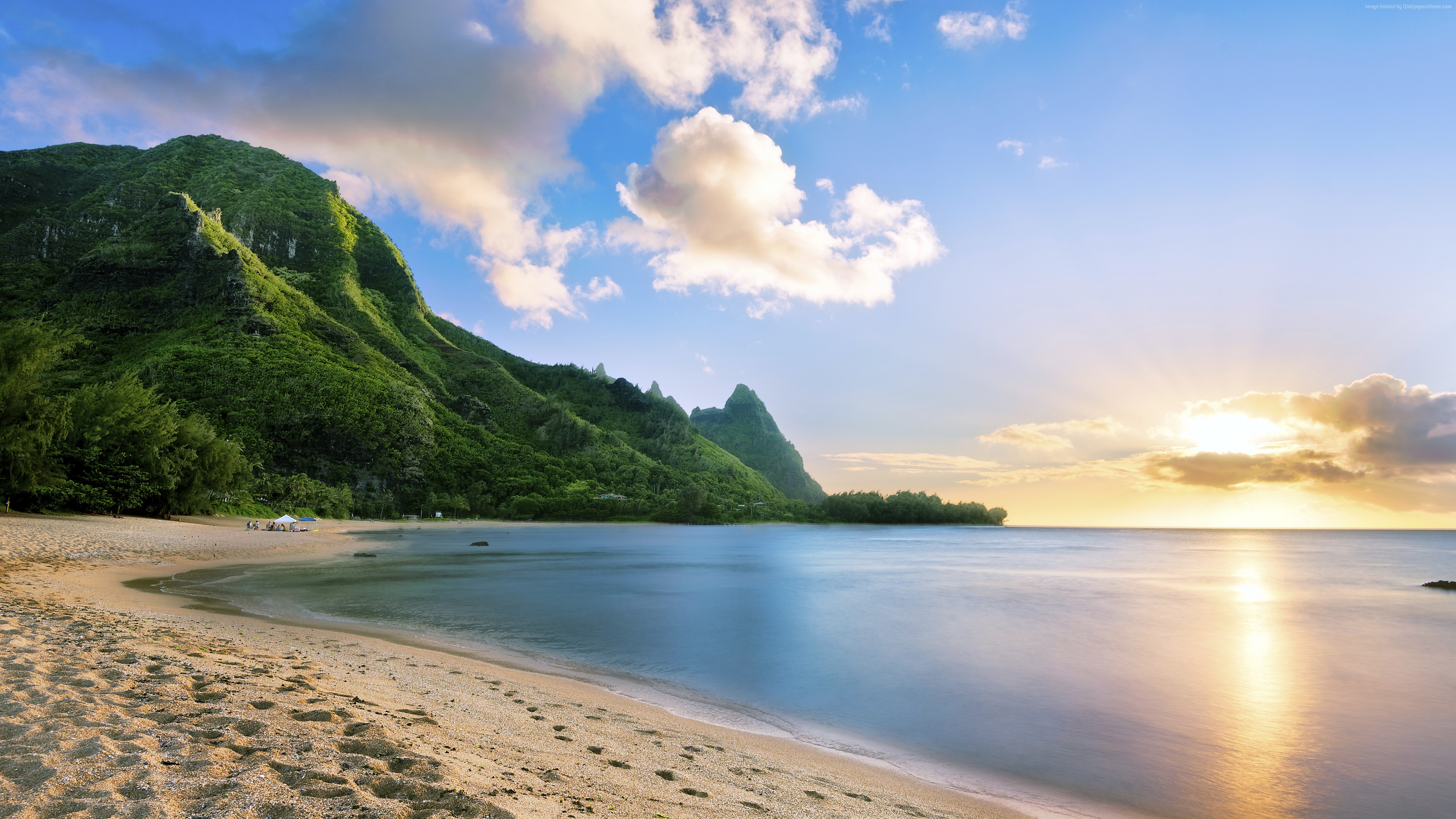 Sunset over a beautiful beach in Hawaii with lush green mountains in the background