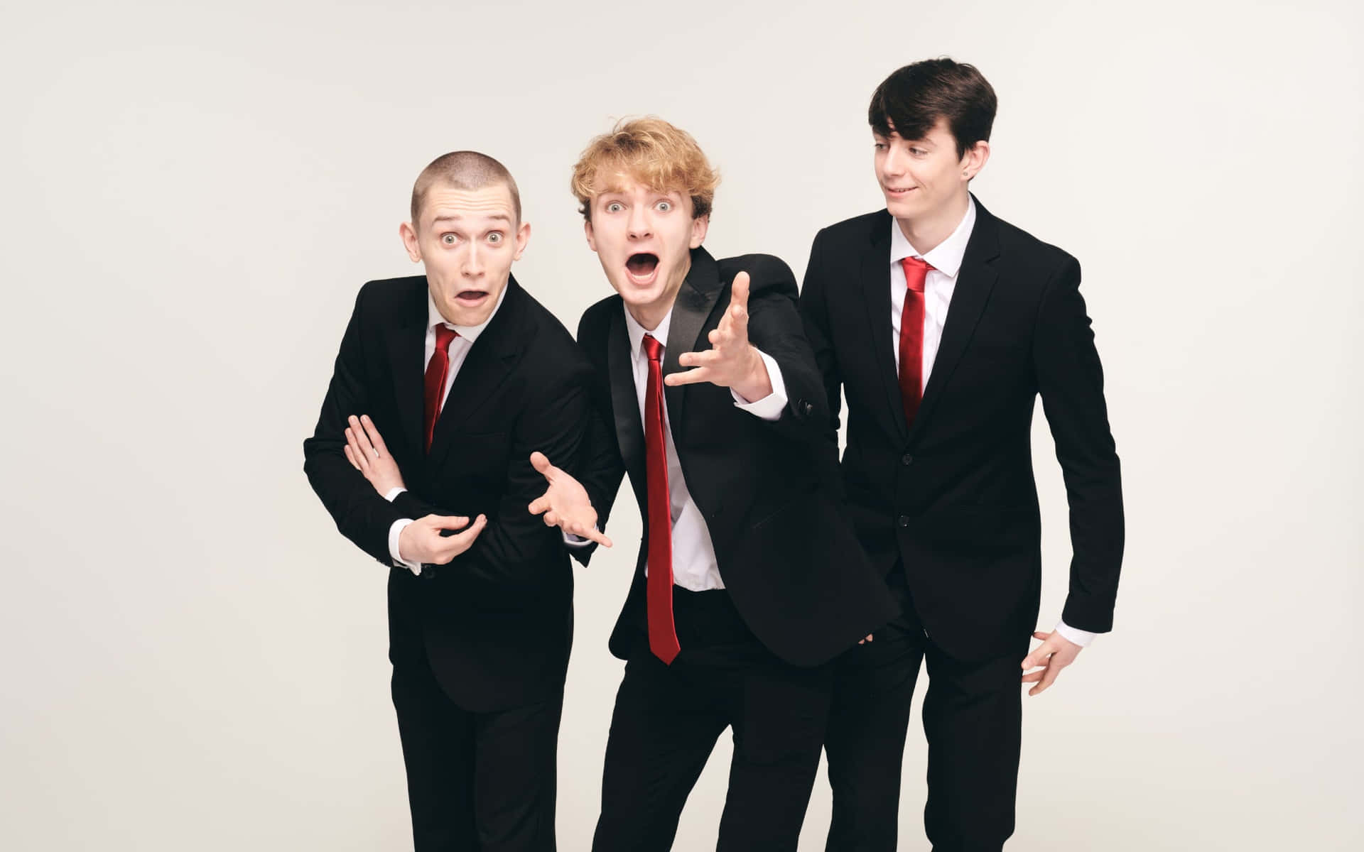 Three Young Men In Suits And Ties Posing Wallpaper