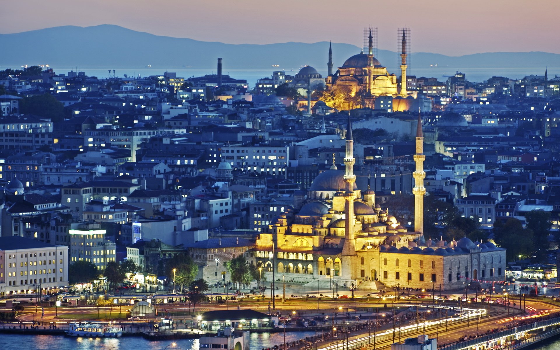A stunning panoramic nightscape of Istanbul, showcasing the Süleymaniye Mosque and the Hagia Sophia, with the Bosphorus and distant hills in the background