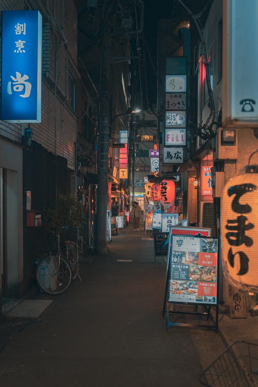 a narrow city street at night with signs on the buildings photo
