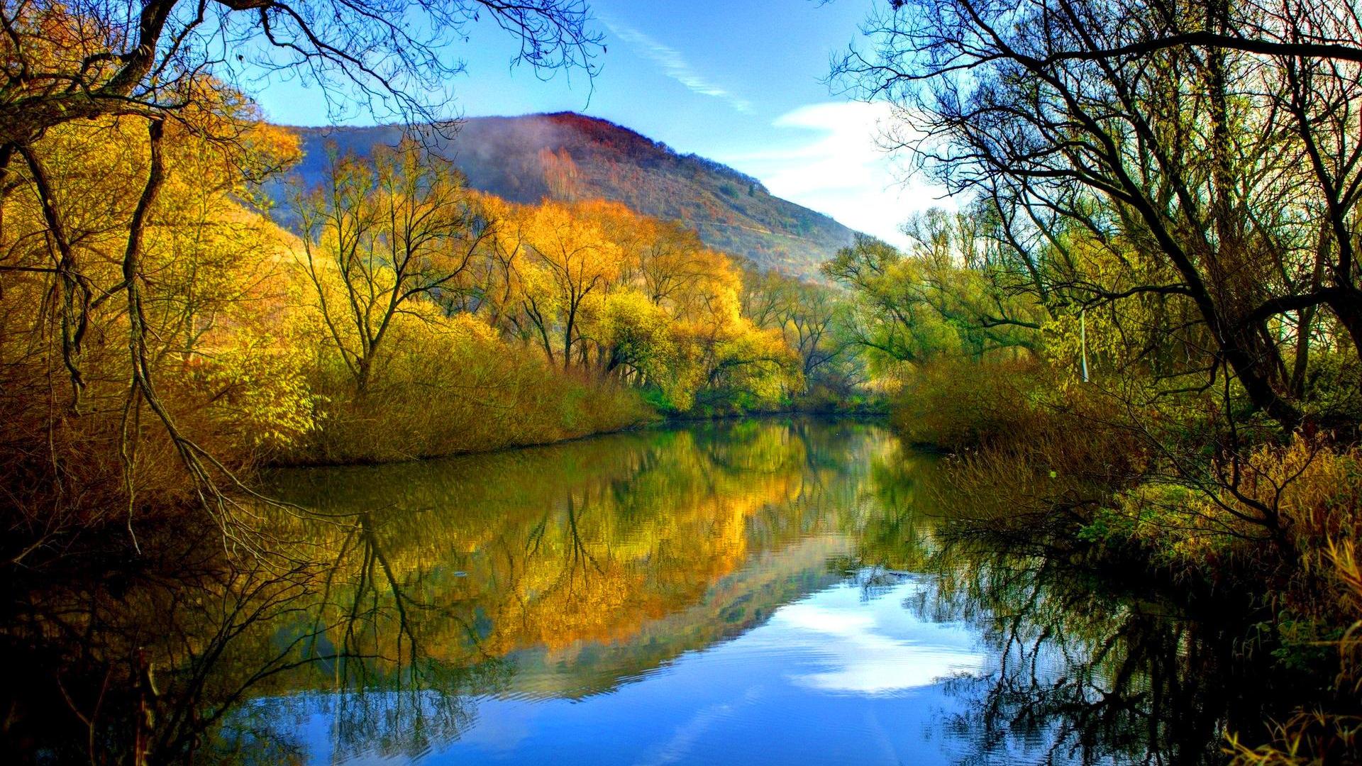 A breathtaking autumn landscape with a calm river reflecting the vibrant colors of the trees and the sky
