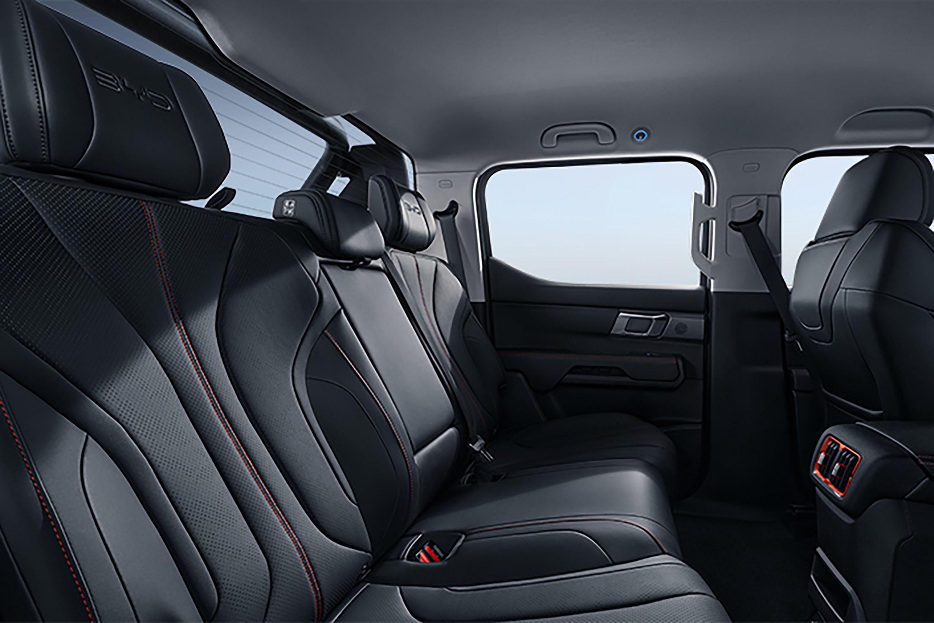 Interior view of a BYD Shark, showcasing black leather seats with red stitching and ample rear passenger space