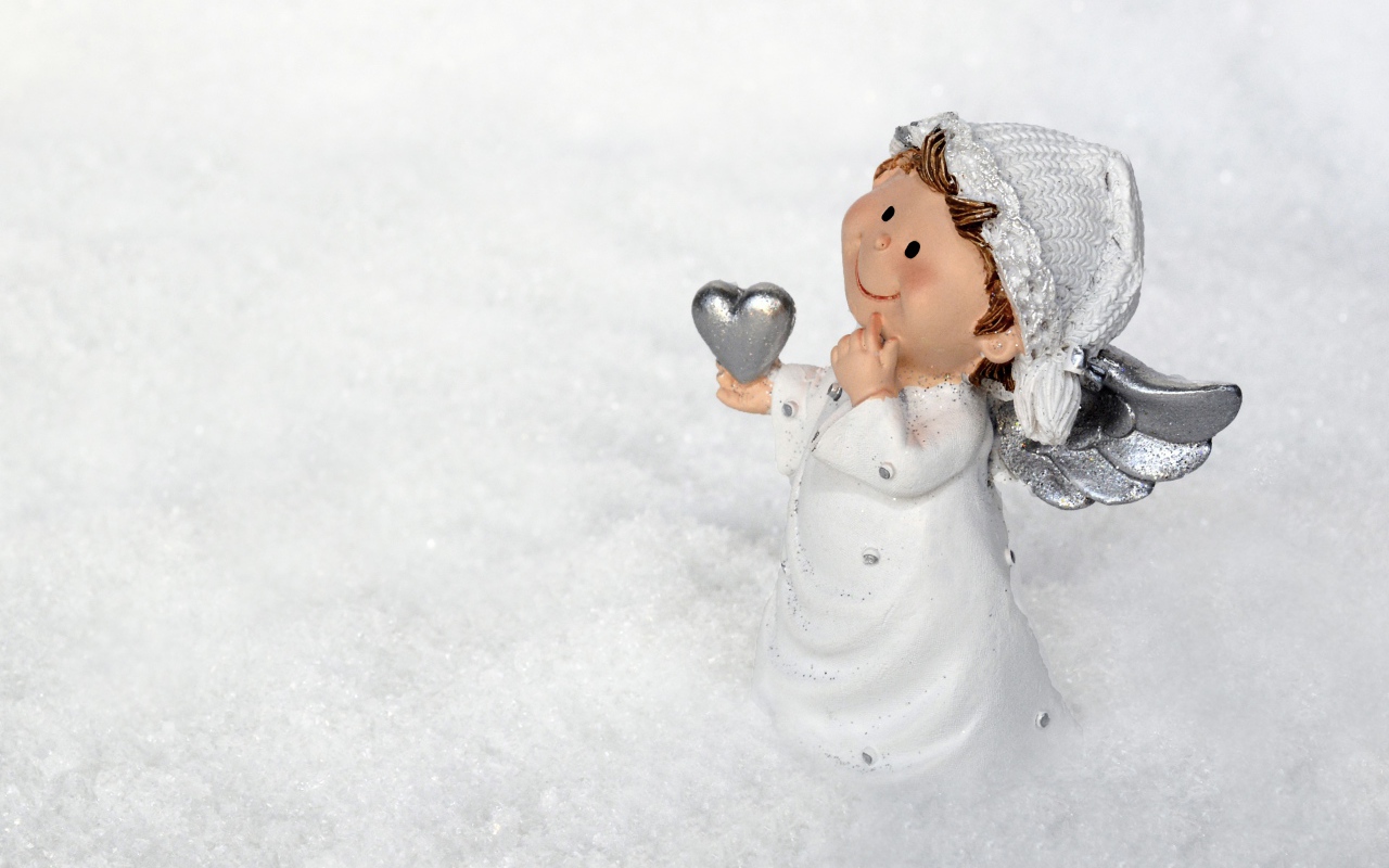 A charming snow angel figurine holds a silver heart, standing serenely in the glistening snow