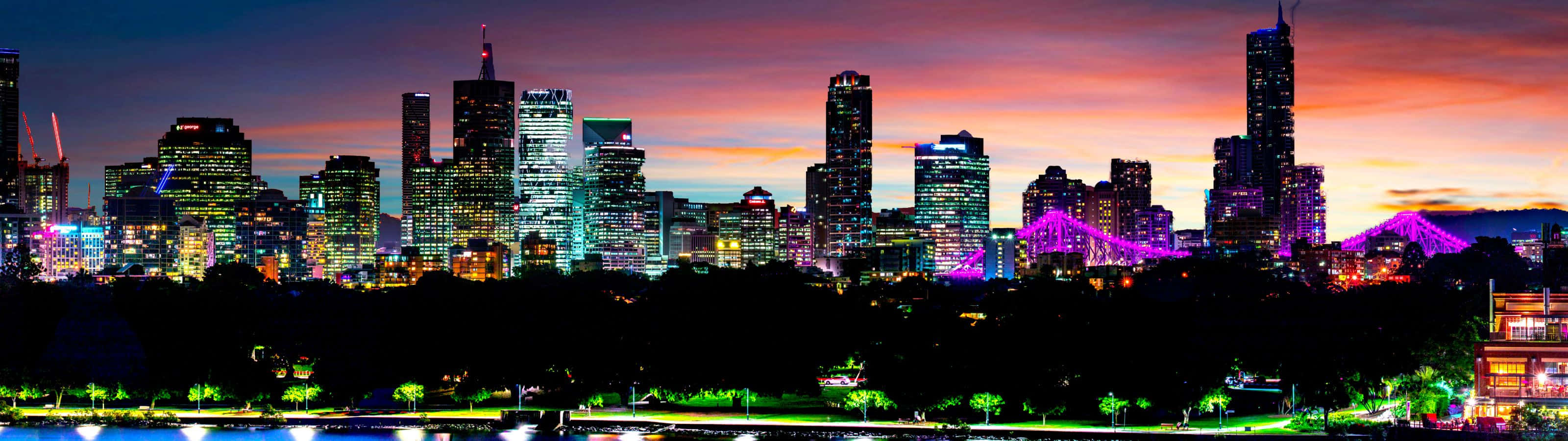 Brisbane City Skyline at twilight with illuminated buildings and purple Story Bridge