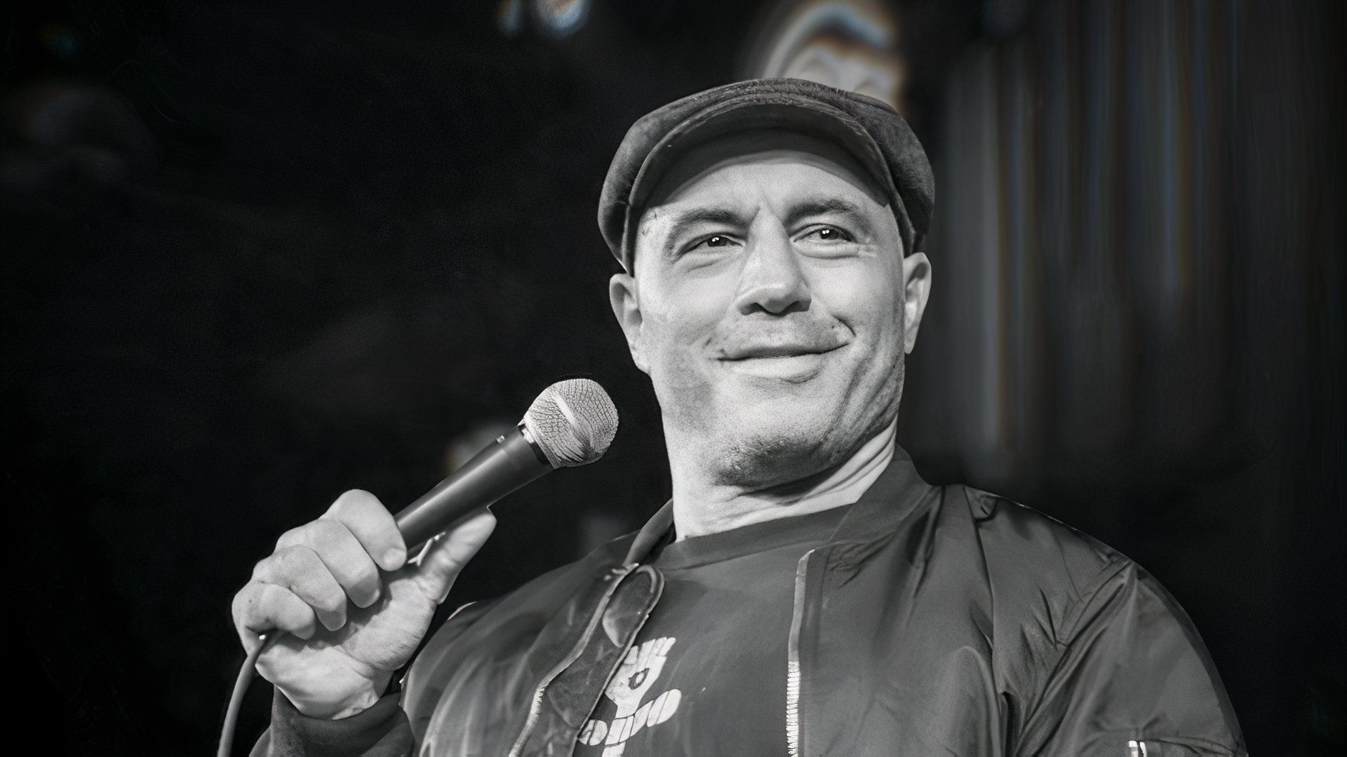 A black and white photo of a man holding a microphone, possibly a comedian or speaker