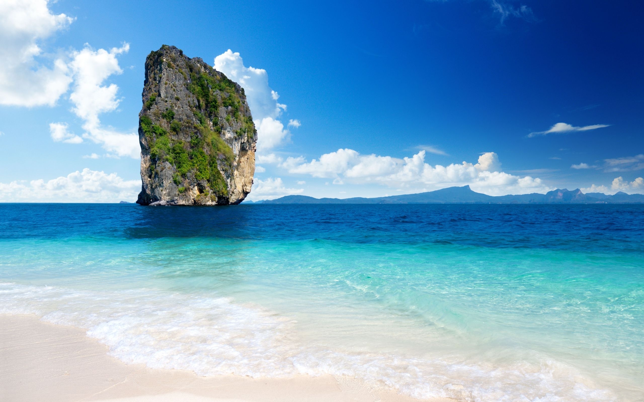 A stunning vista of a tropical paradise, featuring crystal-clear turquoise waters lapping against a white sandy beach, with a majestic rock formation rising from the sea and distant islands on the horizon under a vibrant blue sky