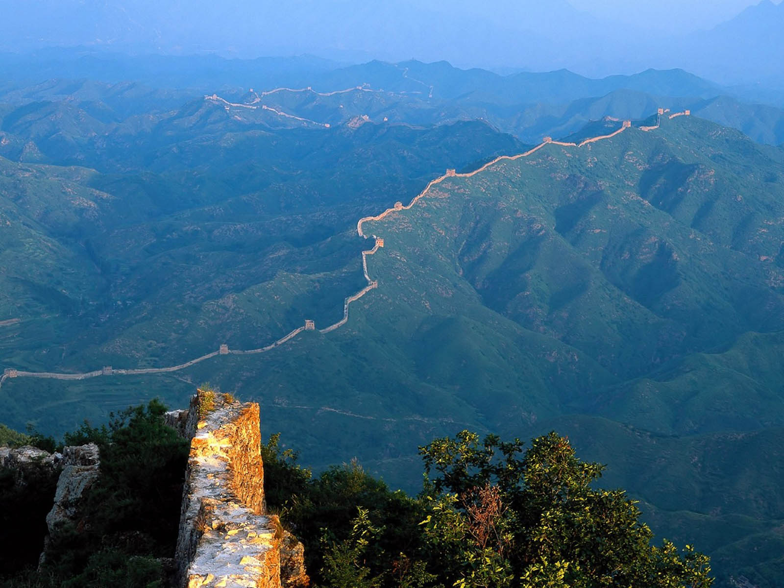 The Great Wall of China winds through lush green mountains, a testament to ancient engineering and a symbol of China's rich history