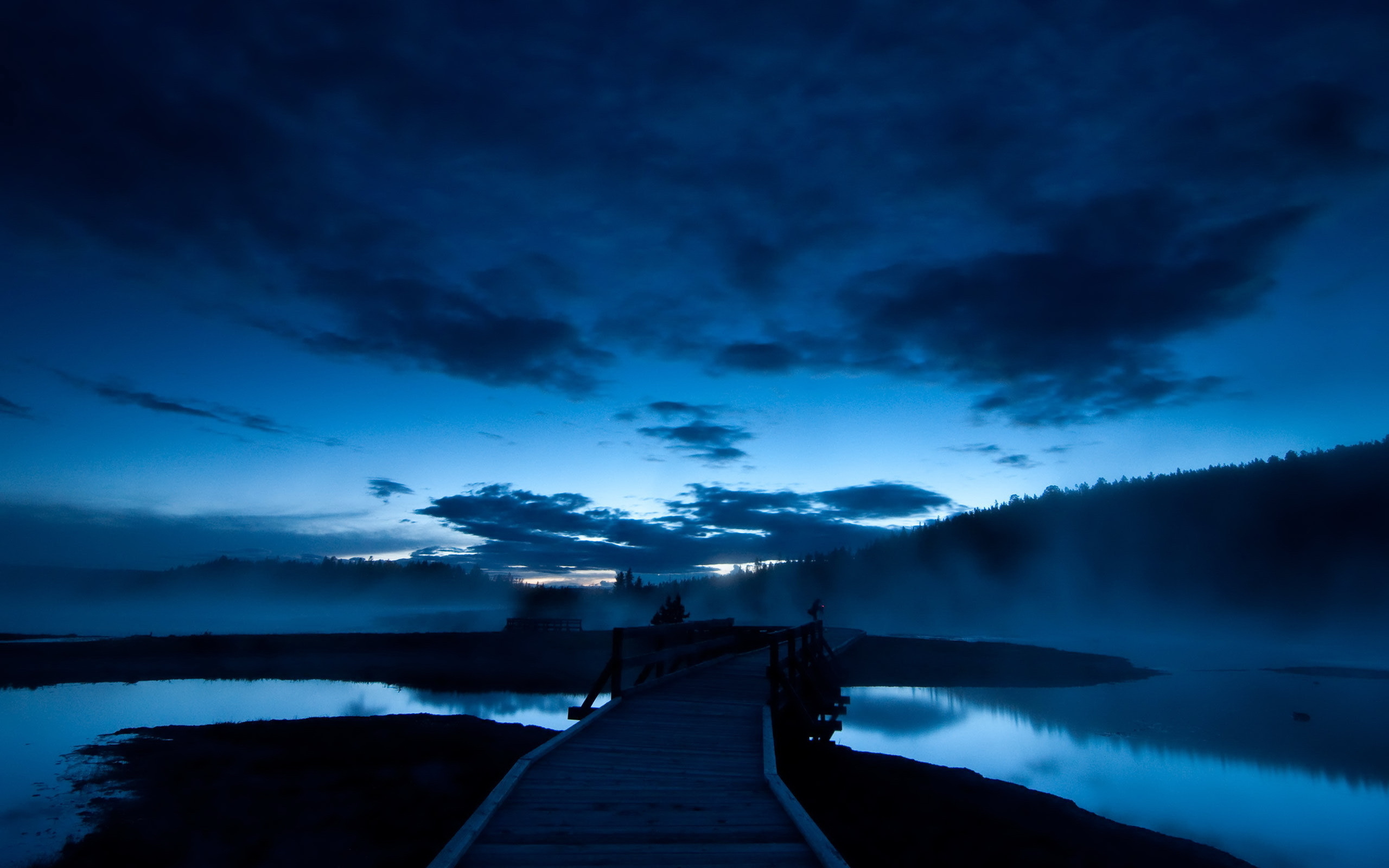 A serene twilight landscape with a wooden boardwalk extending over a tranquil lake, surrounded by misty forests and a dramatic sky