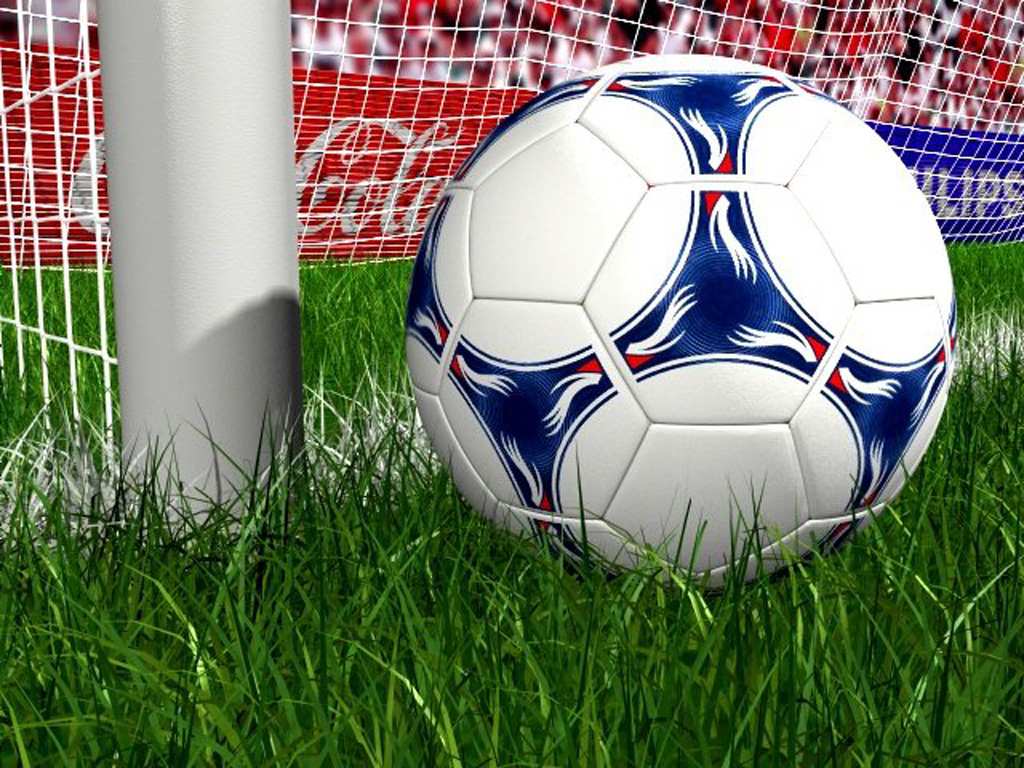 Soccer ball on a lush green field near the goalpost
