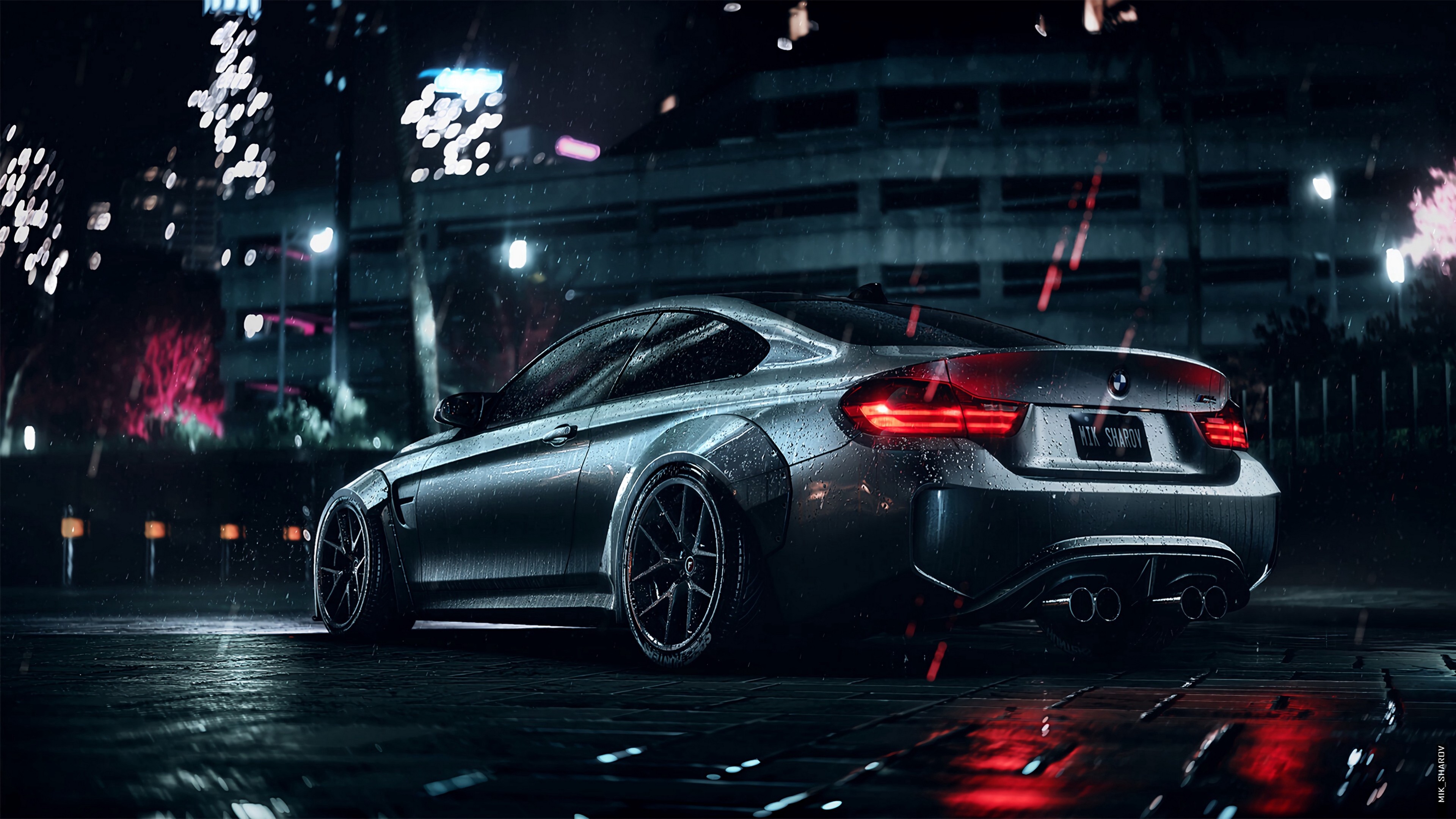 A silver BMW M4 coupe parked on a wet city street at night, with fireworks in the background
