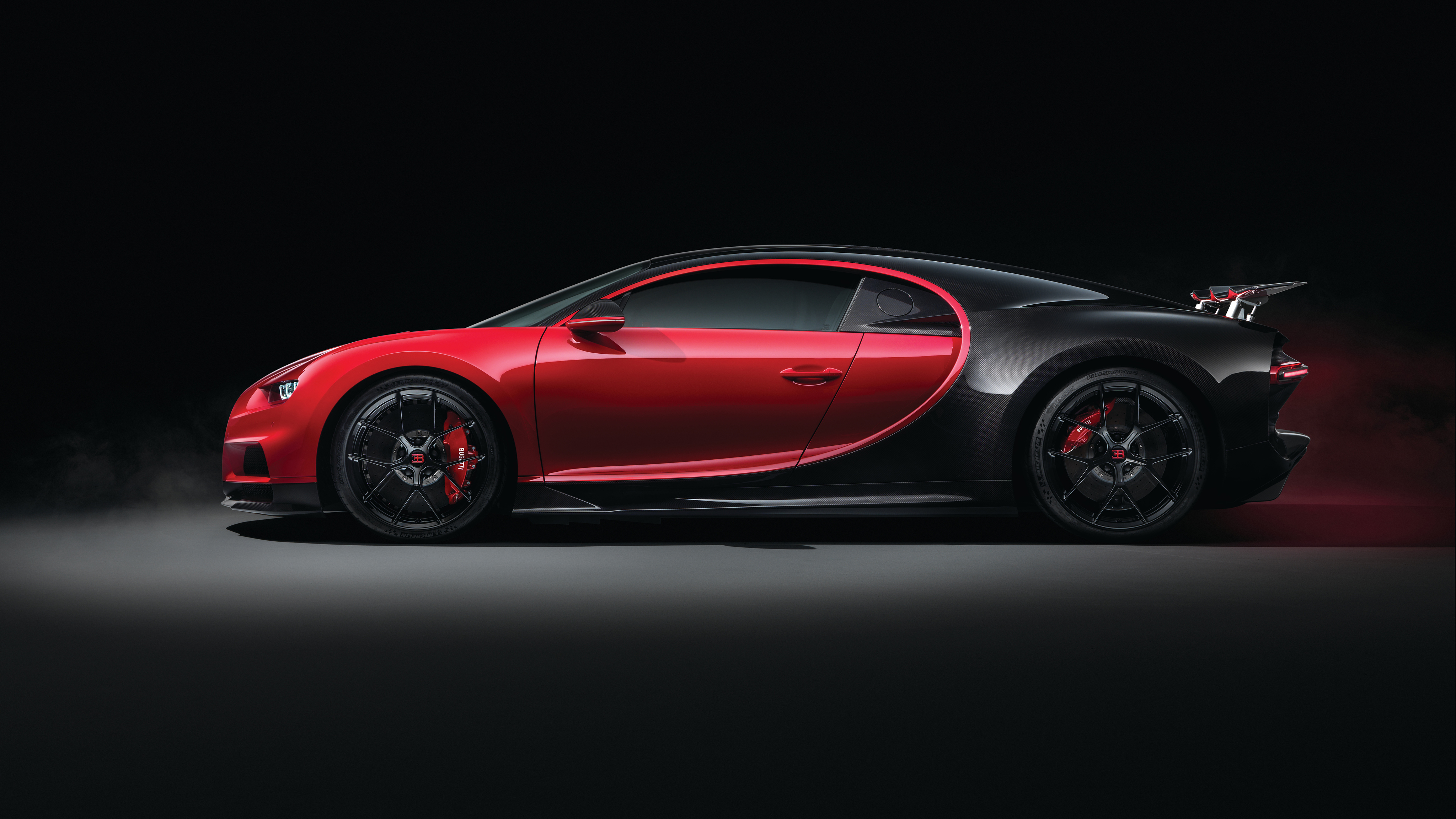 A side view of a red and black Bugatti Chiron Super Sport, highlighting its sleek design and powerful presence