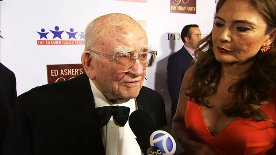 Legendary Actor Edward Asner Engaging In A Friendly Conversation With Wallpaper