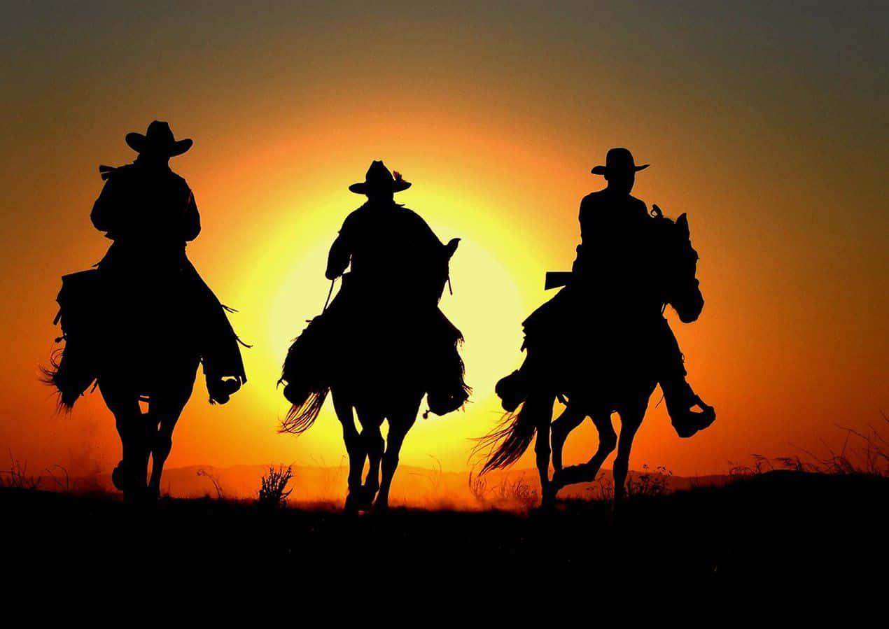 Sunset Silhouettes Of Three Western Cowboys Desktop