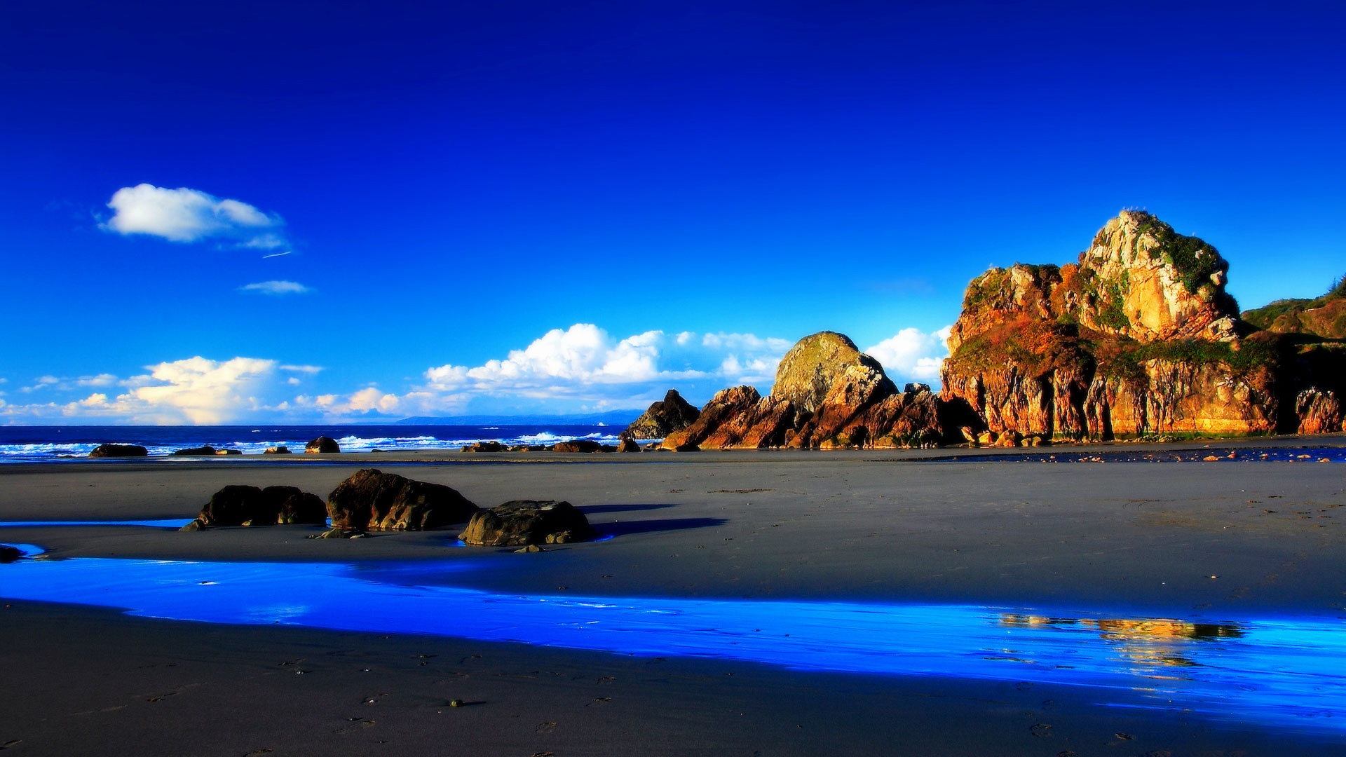 Vivid blue beach with rock formations under a vibrant blue sky