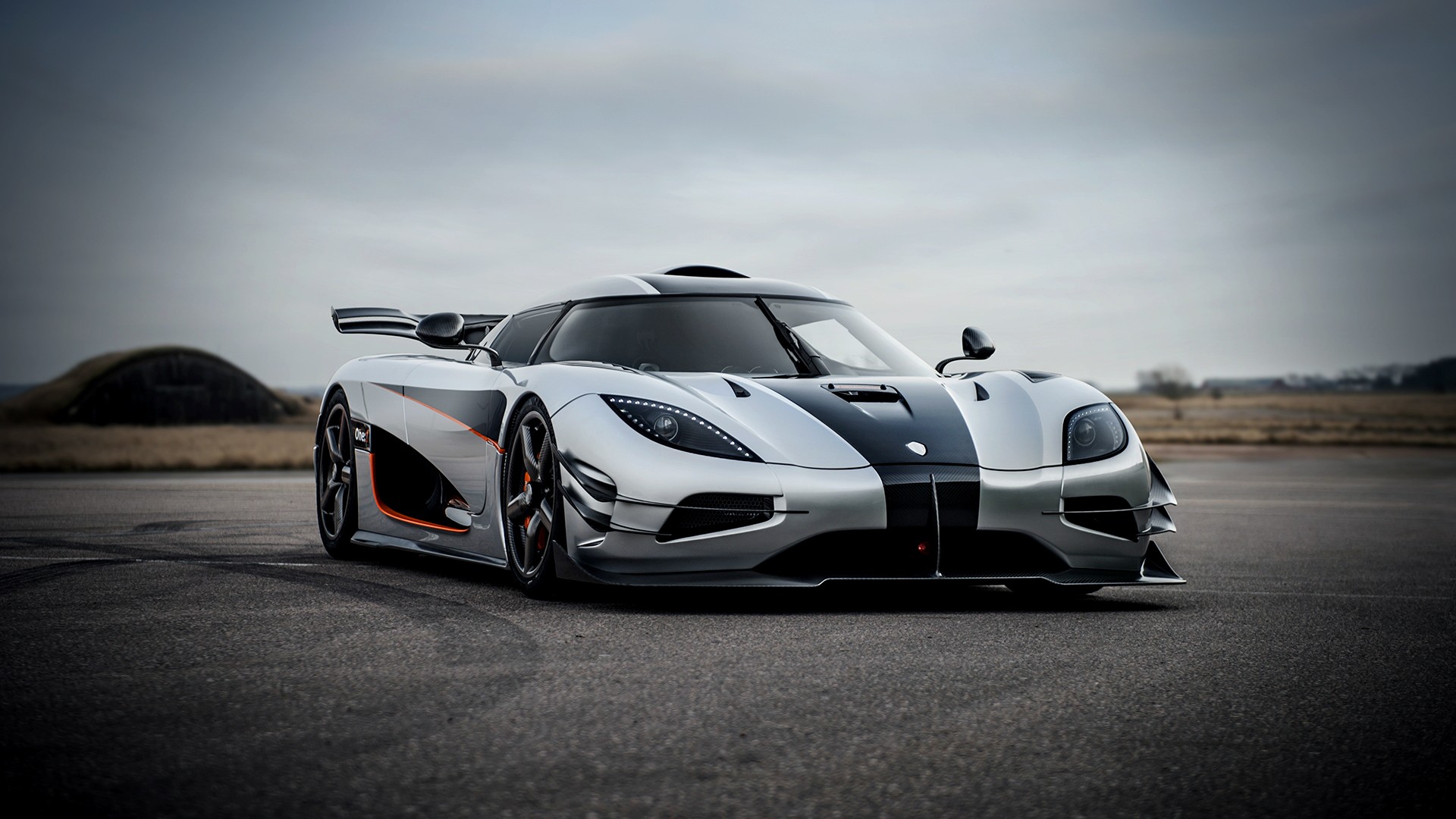 A silver and black Koenigsegg Regera parked on a tarmac, showcasing its sleek design and powerful presence