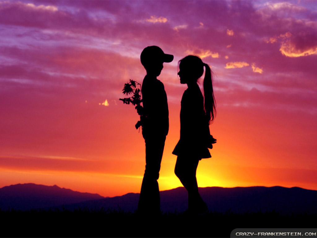 Silhouette of a young boy and girl holding flowers at sunset, symbolizing young love and romance