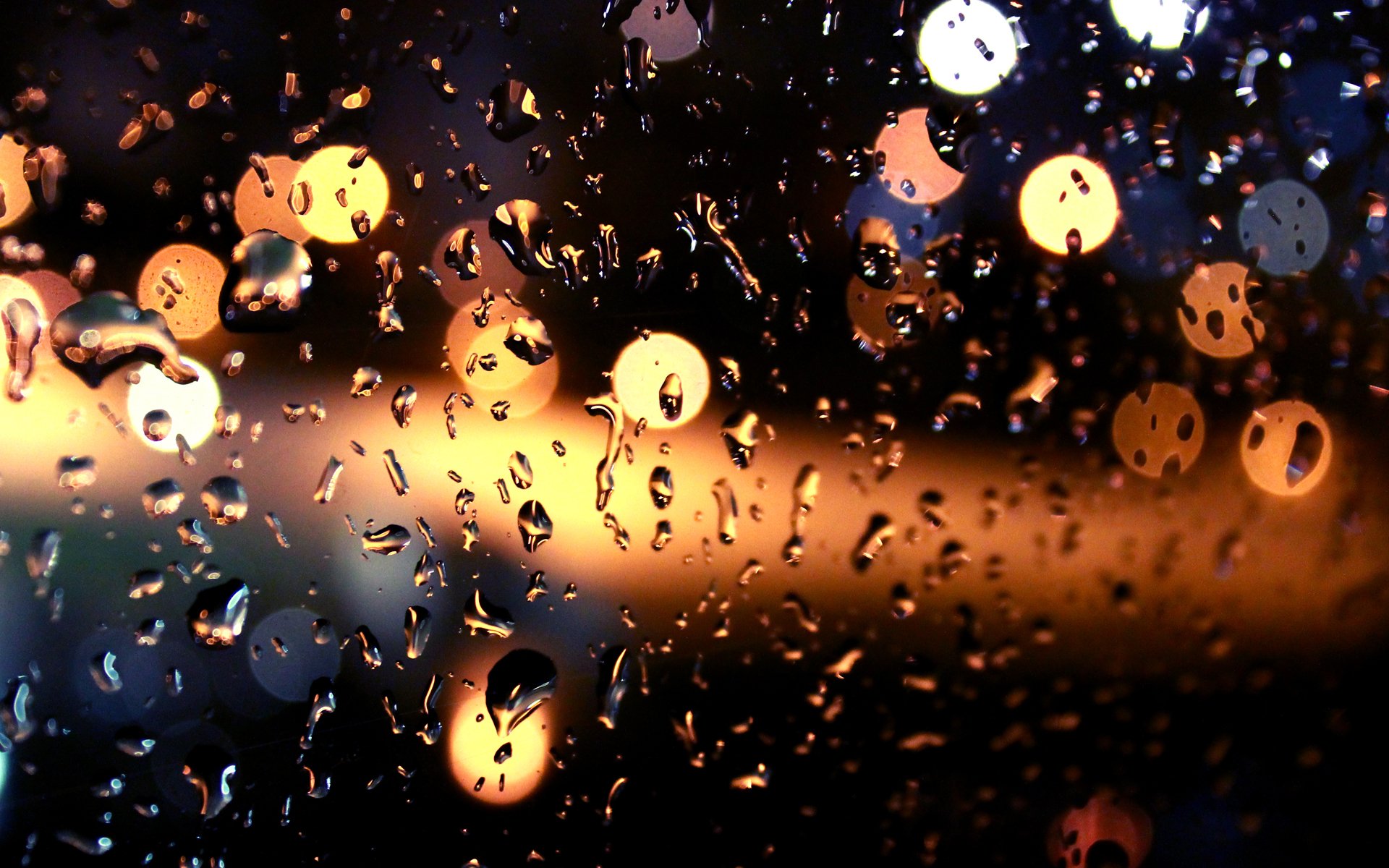 Raindrops on a window pane at night, with blurred city lights in the background