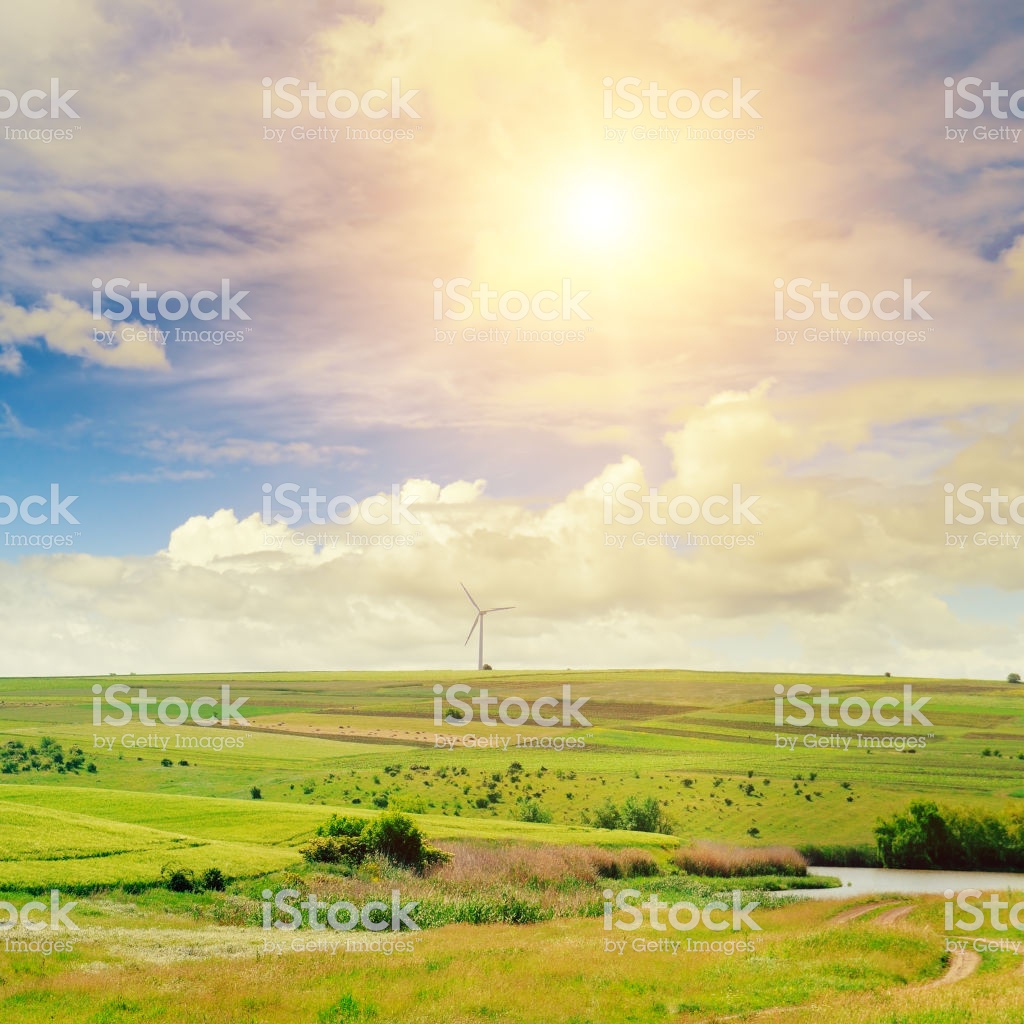 Hilly Green Field Windmill And Sun On Blue Sky Background Stock