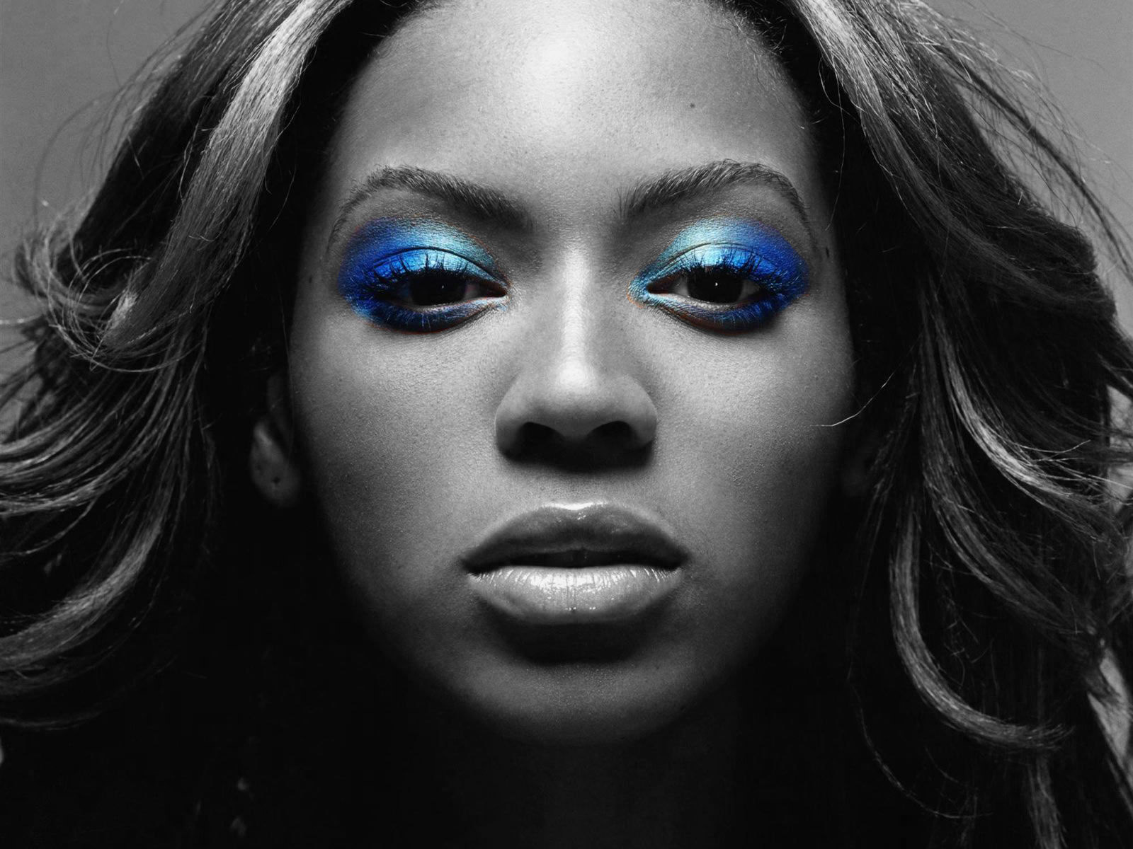 Close-up black and white portrait of Beyonce with vibrant blue eyeshadow, emphasizing her captivating gaze and beauty