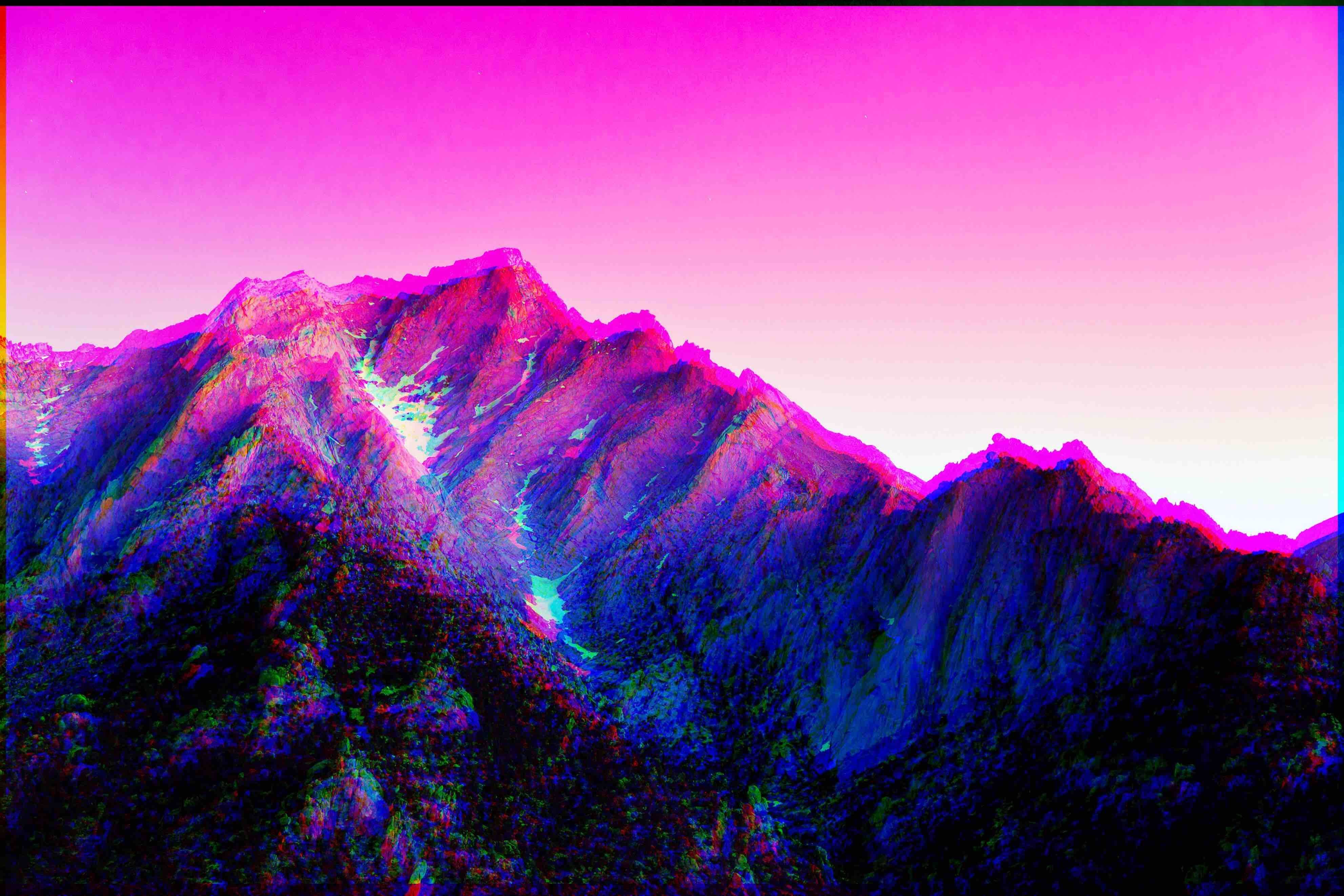A vibrant, glitch-art image of a mountain range against a neon pink sky. The mountains are rendered in shades of purple and blue, with a chromatic aberration effect adding a sense of depth and otherworldliness