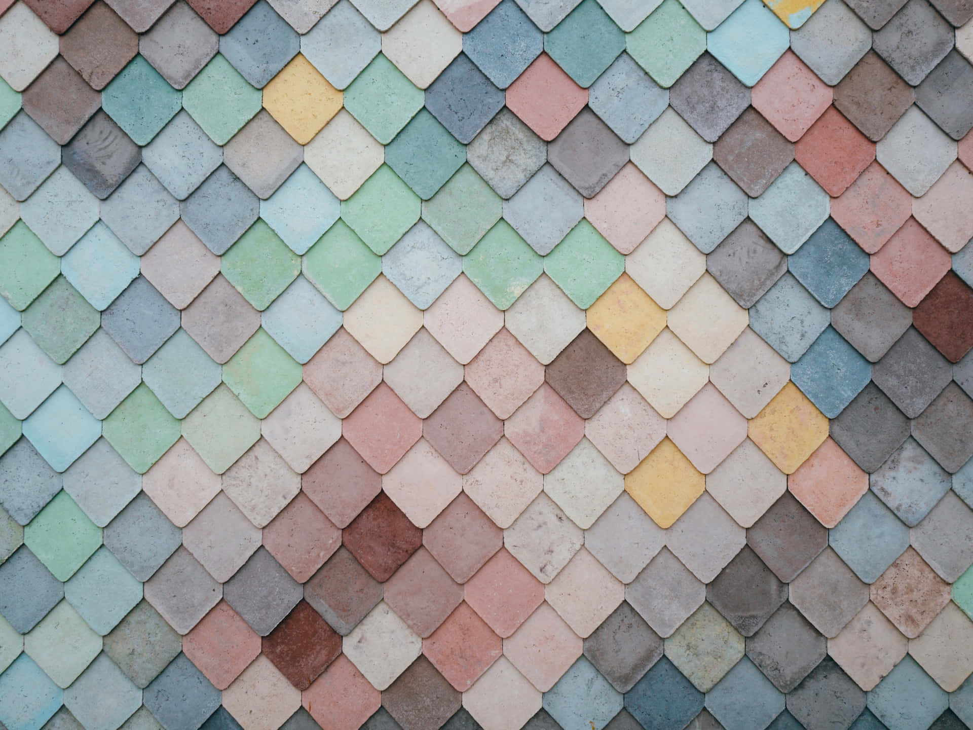 A wall covered in colorful, overlapping diamond-shaped tiles, creating a textured and visually appealing pattern