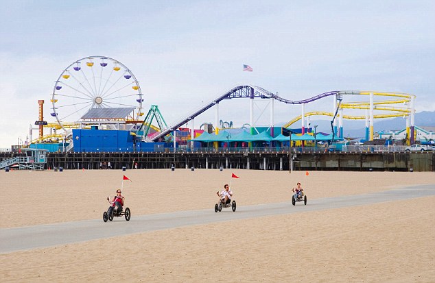 Riding Tricycles On Santa Monica Beach With The Pier In Background