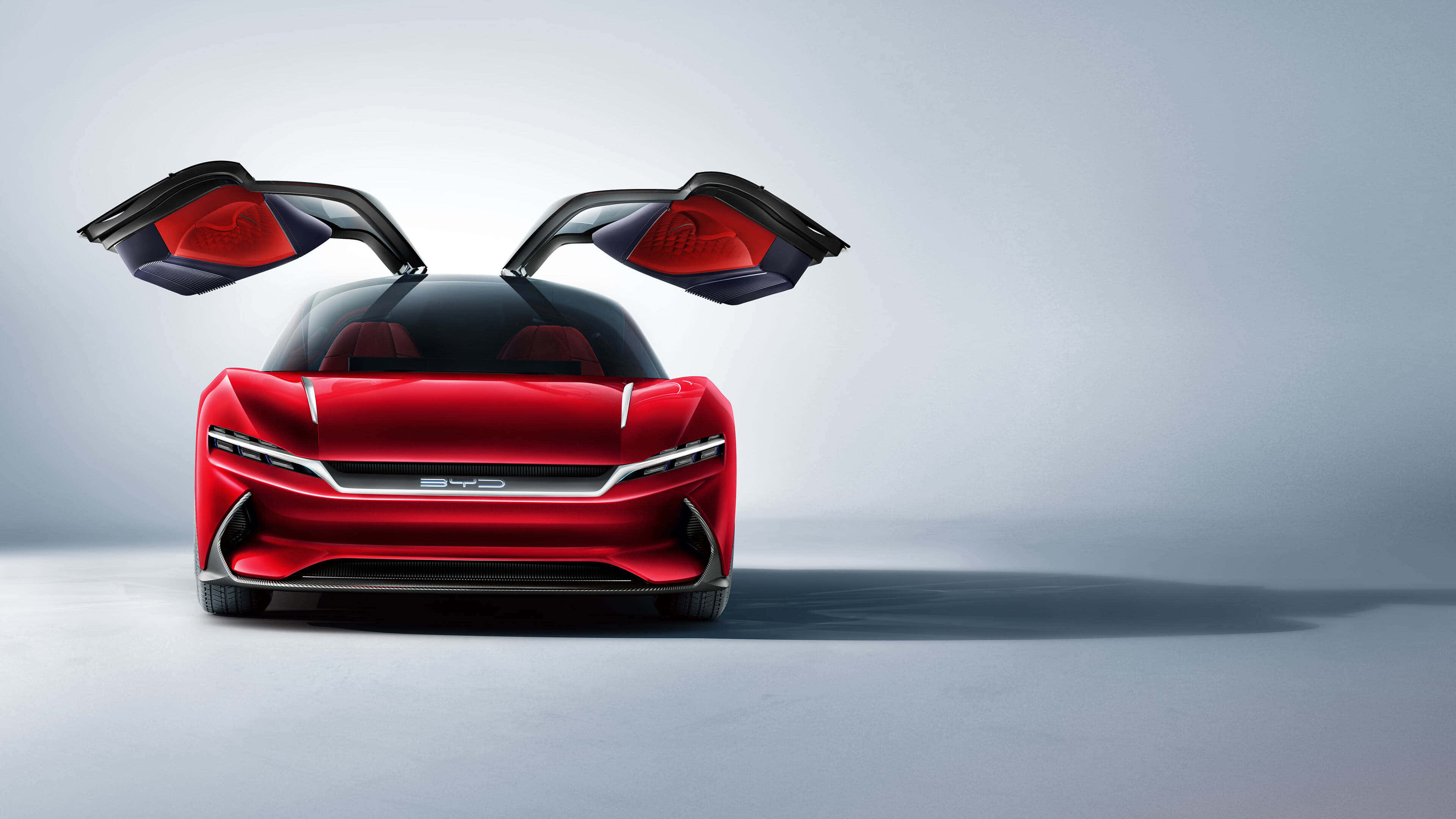 BYD's futuristic red concept car, possibly the Shark, with its iconic butterfly doors open, showcasing a sleek and sporty design against a minimalist background