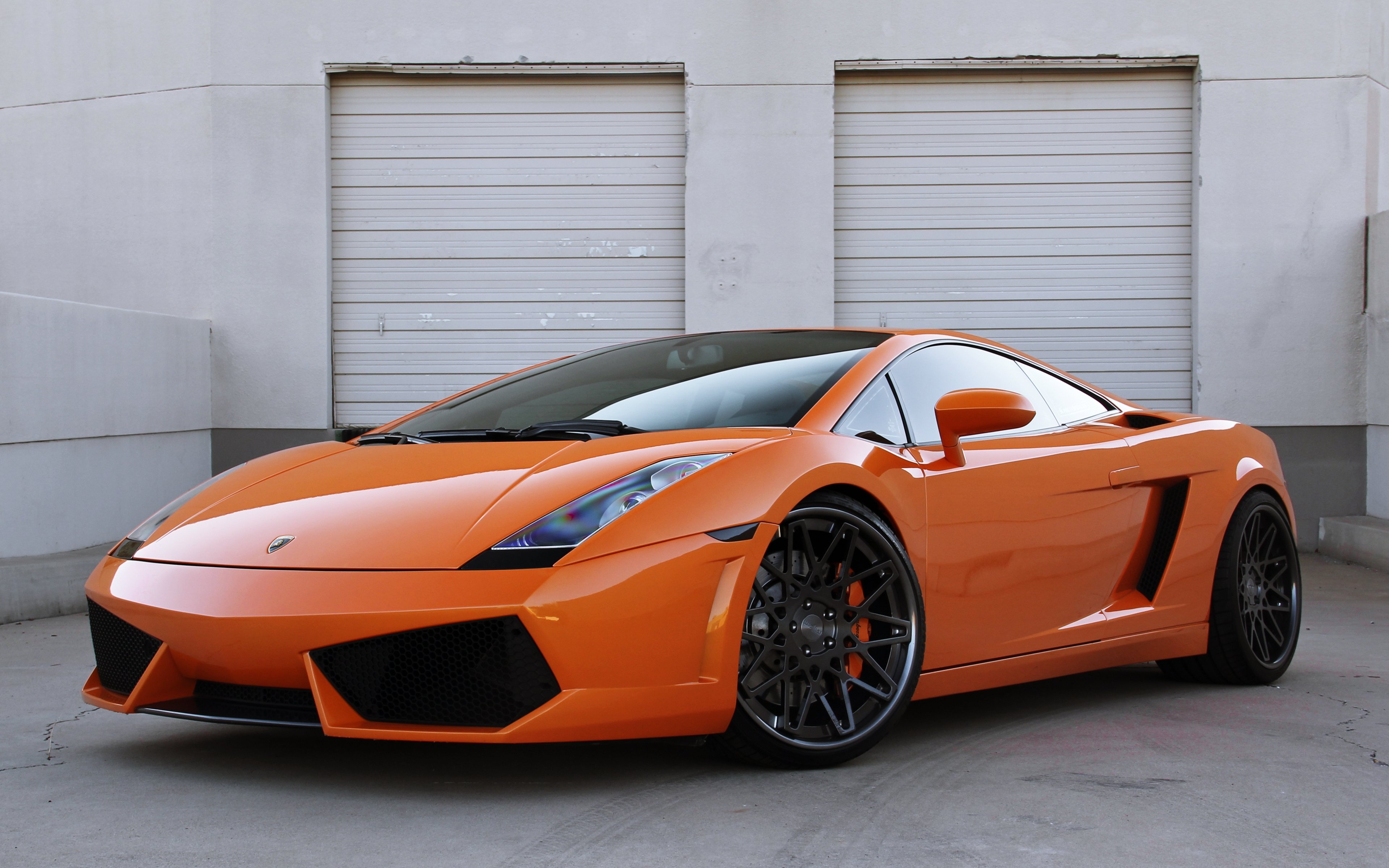 Bright Orange Lamborghini Gallardo parked in front of a white garage door