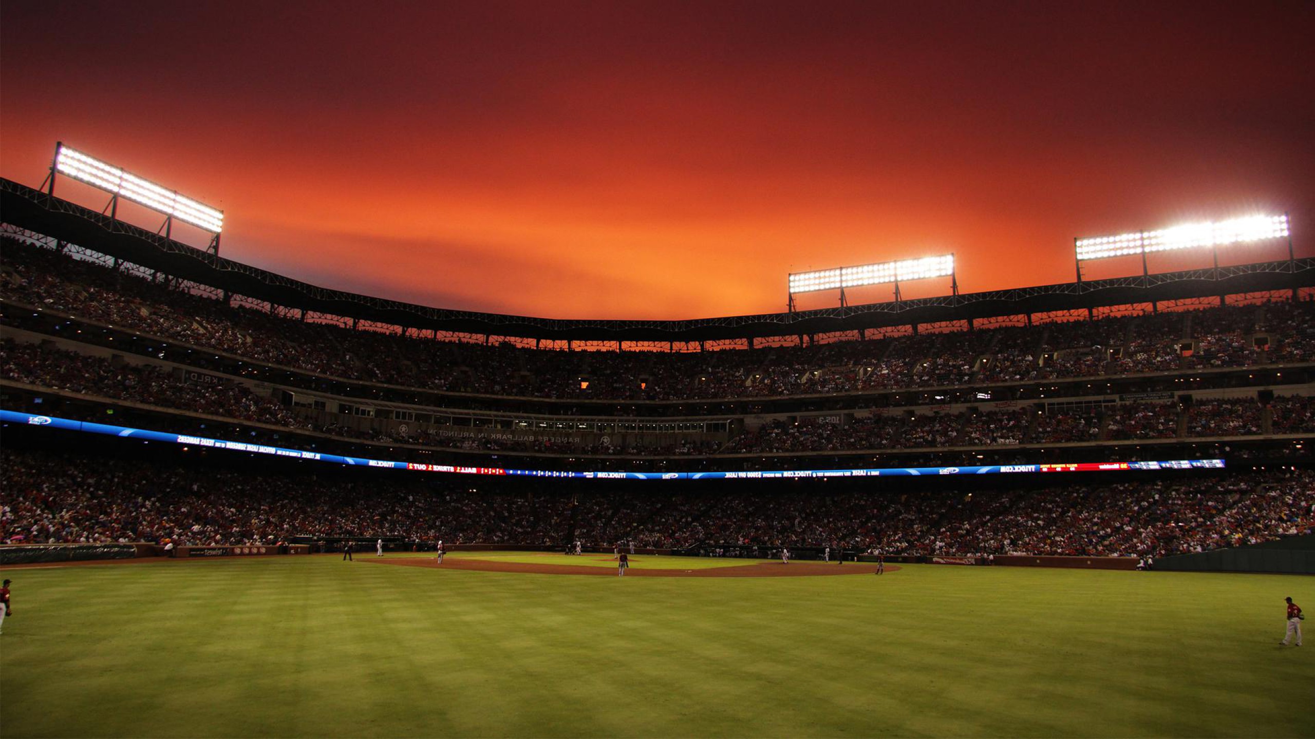 A baseball stadium at sunset, filled with cheering fans, as the game unfolds on the vibrant green field
