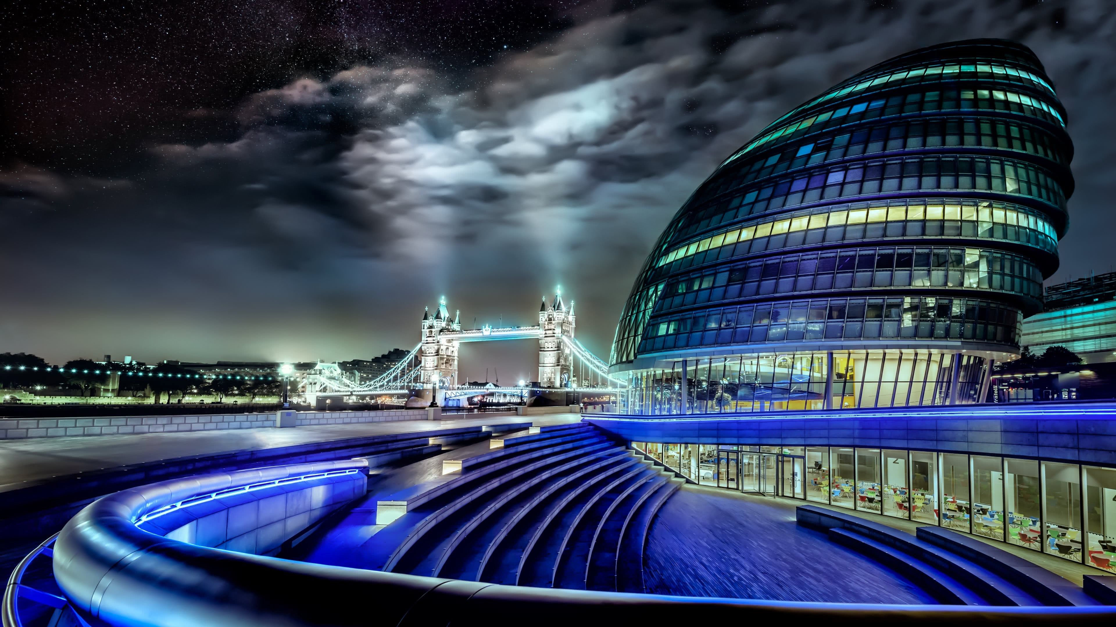 A stunning night view of London's City Hall and Tower Bridge, illuminated under a starry sky