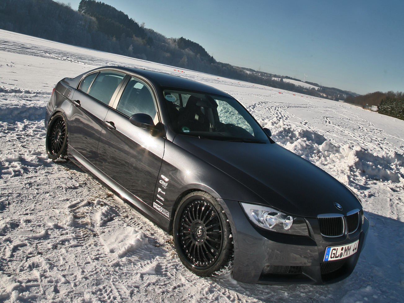 A dark gray BMW sedan parked on a snowy field, showcasing winter driving capabilities