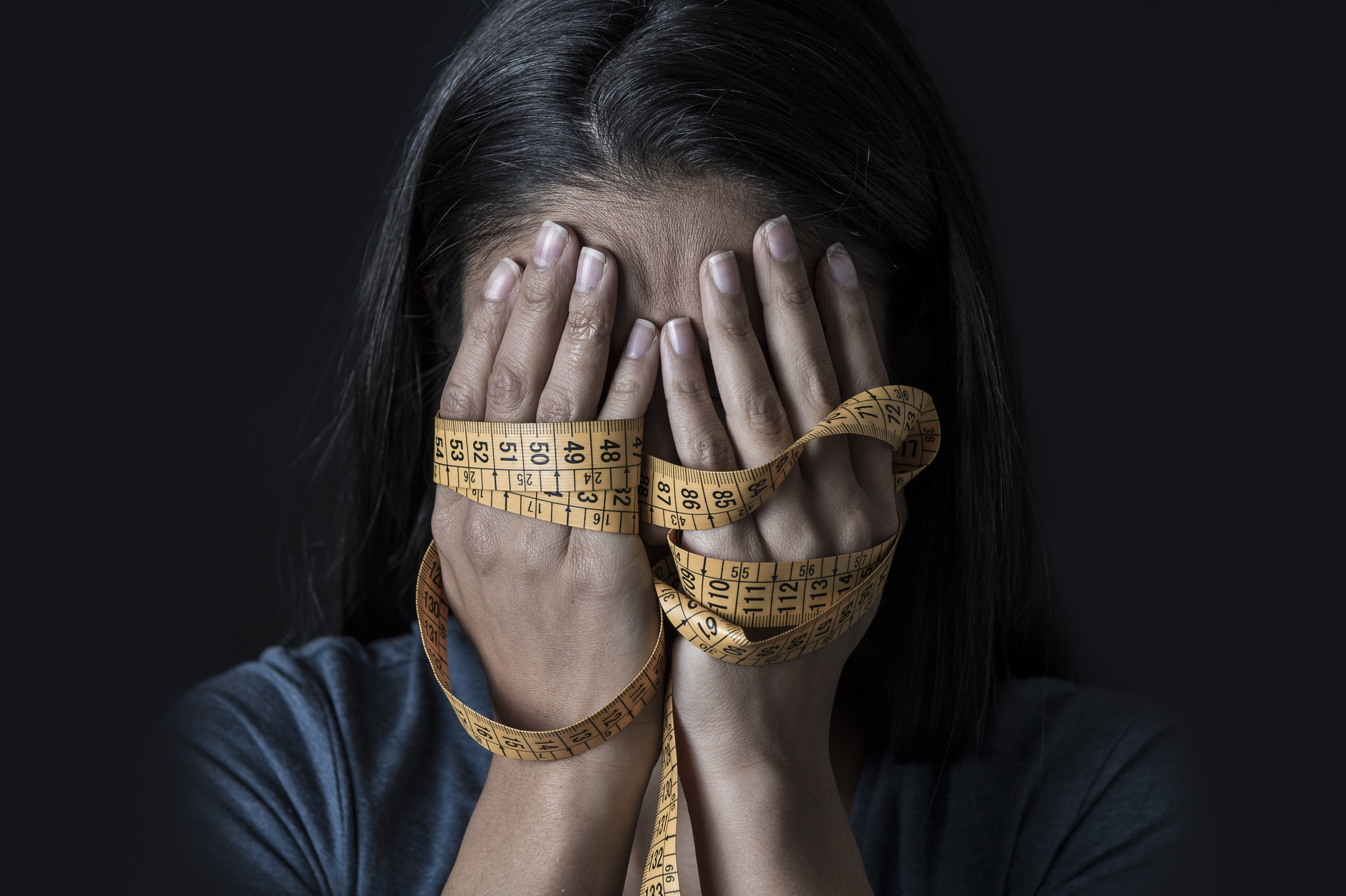 Close Up Hands Wrapped In Tailor Measure Tape Covering Face Of