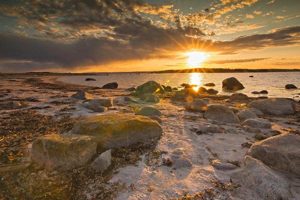 gray rocks on sea shore during sunset photo Free Nature Image on