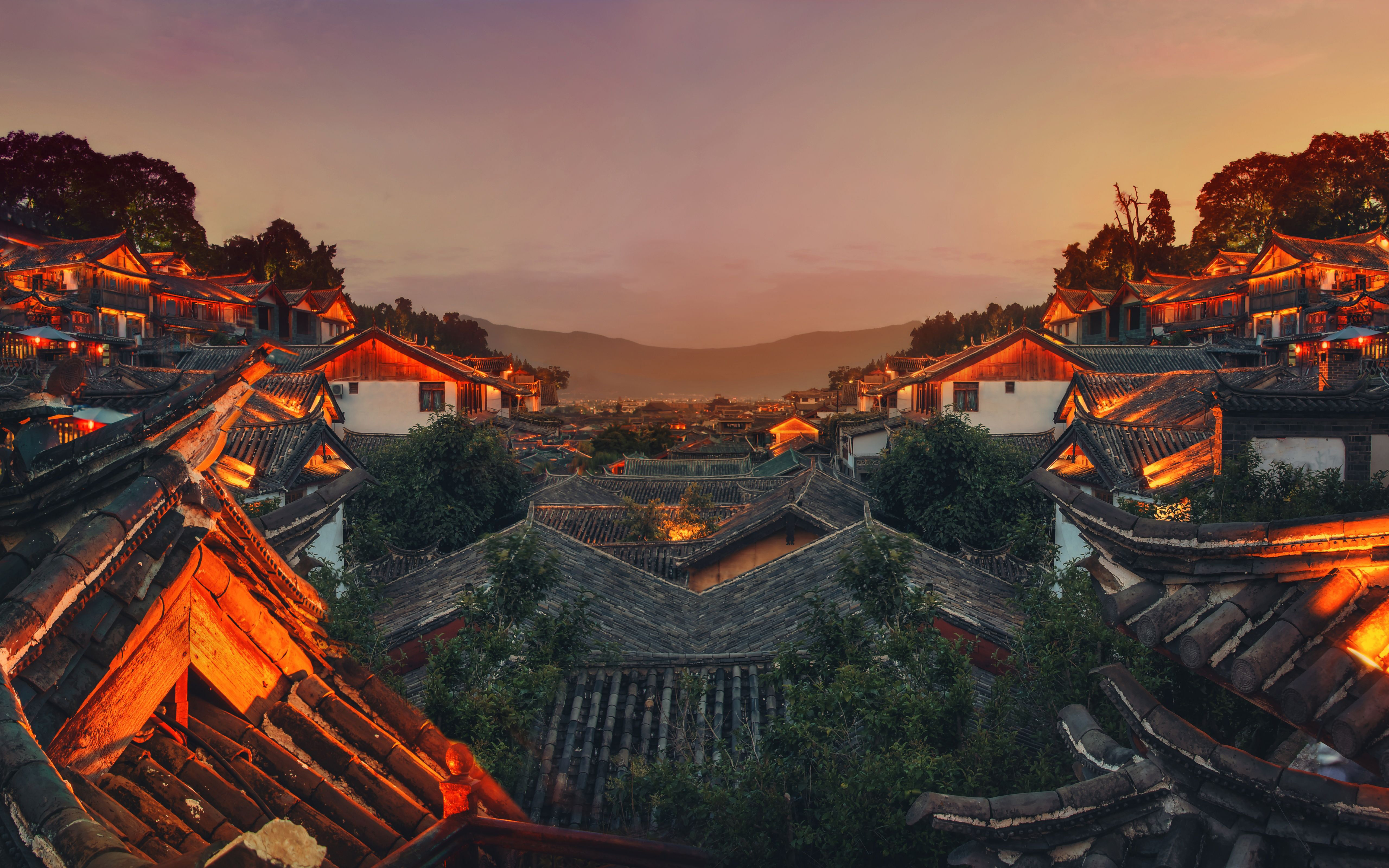 Sunset over a traditional Chinese village with illuminated rooftops