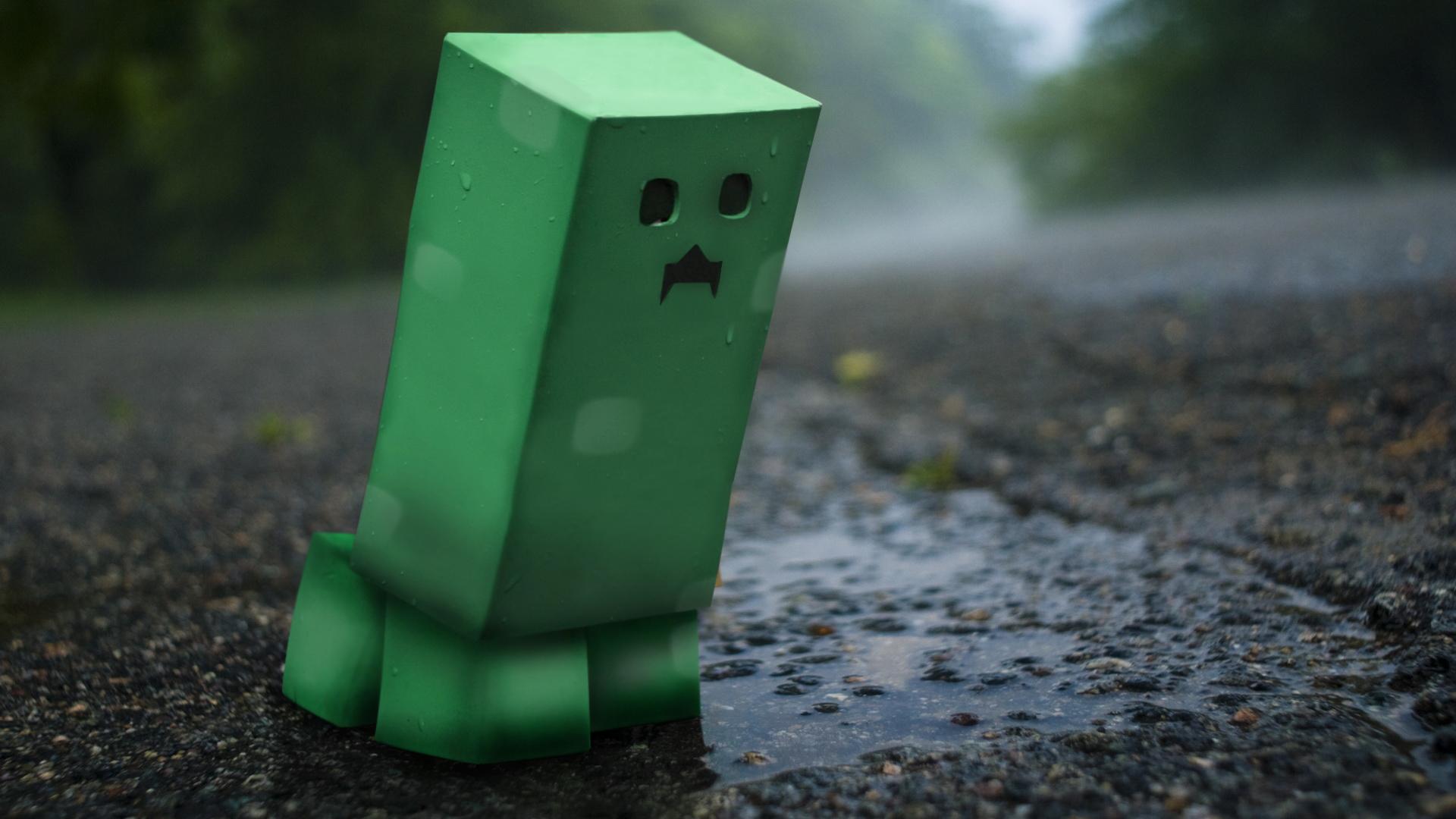 A lonely Minecraft Creeper stands on a rain-soaked road, looking forlorn
