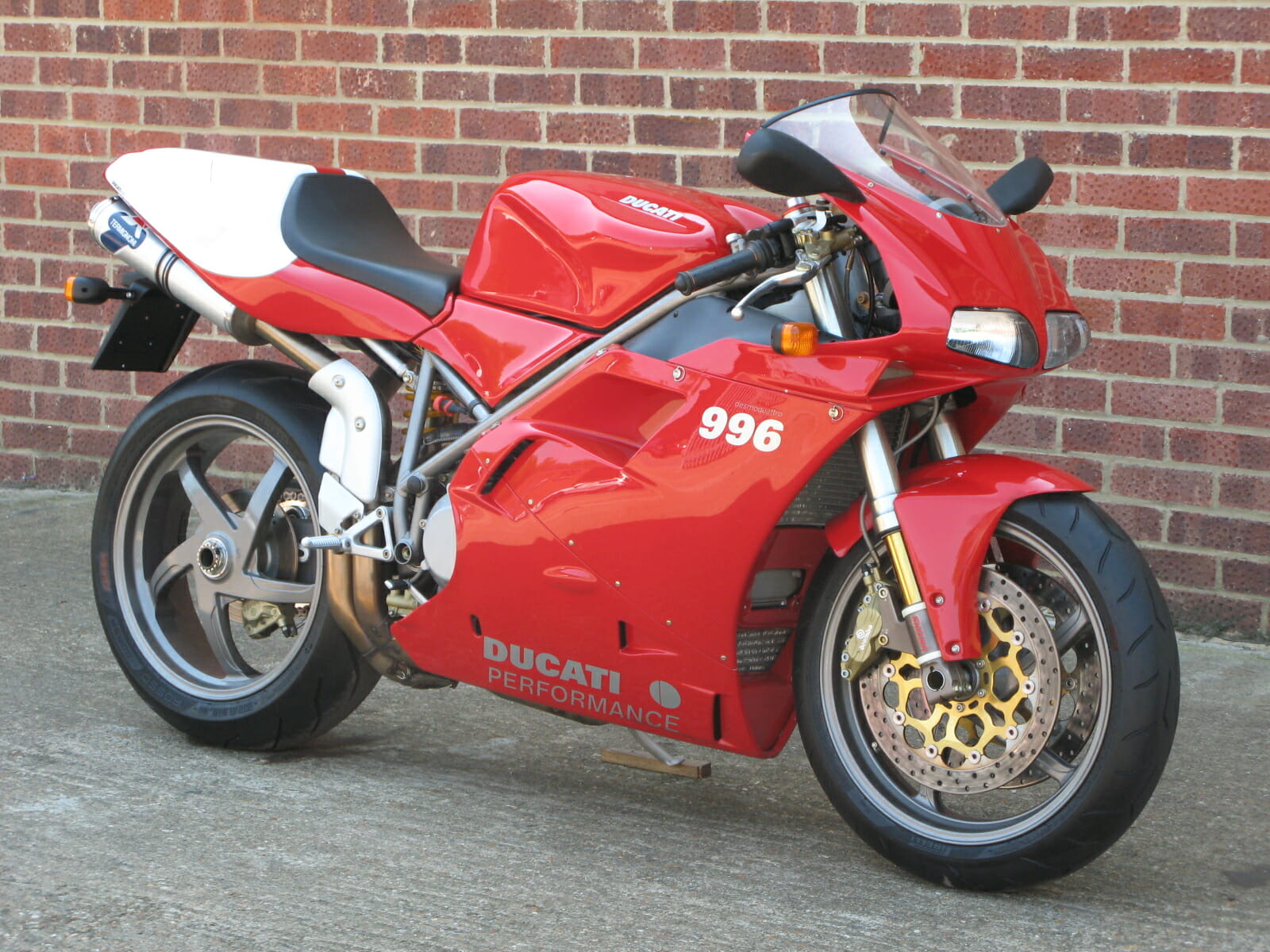 Red Ducati 996 Motorcycle Parked in Front of Brick Wall